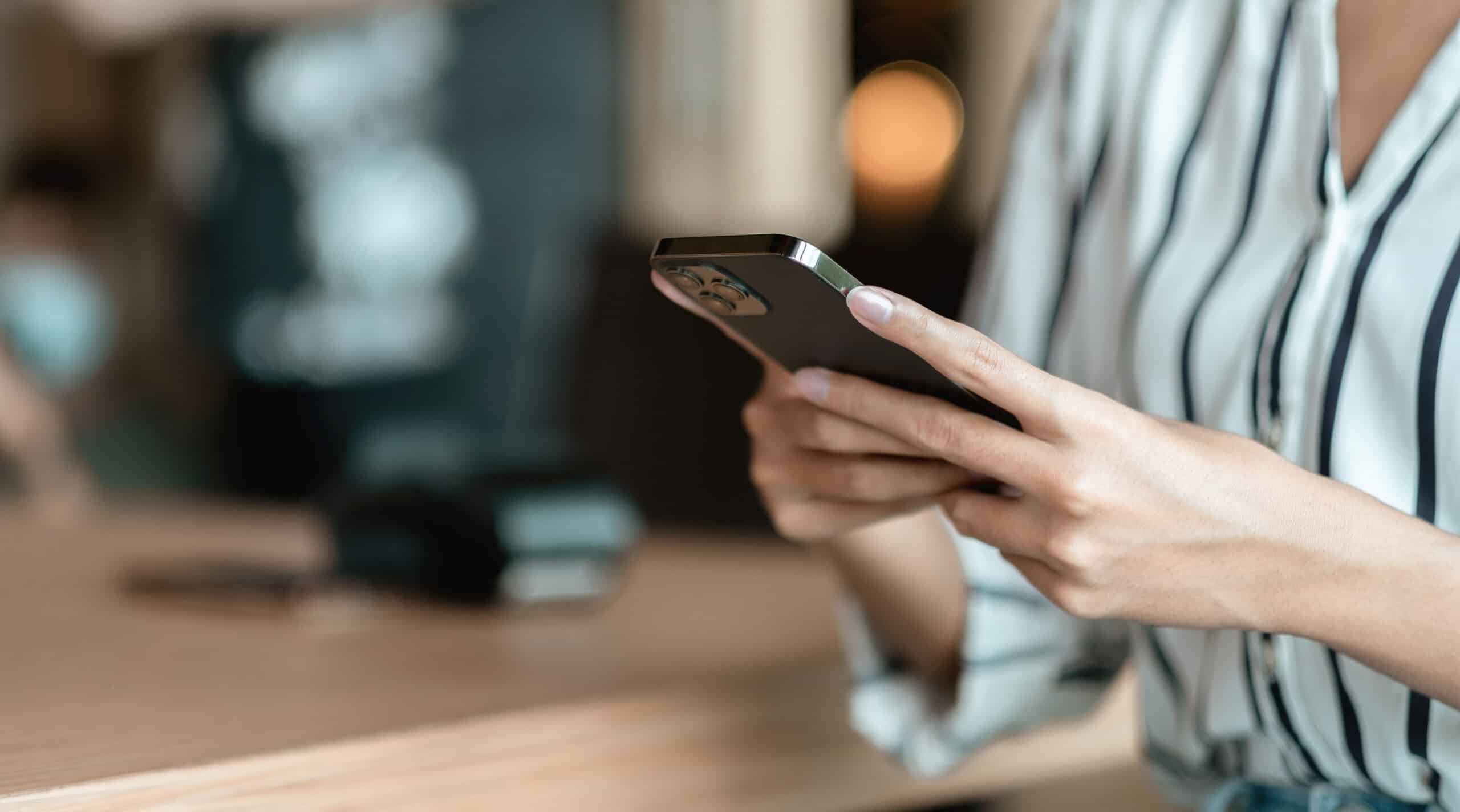 Hands holding a smartphone at a café table.