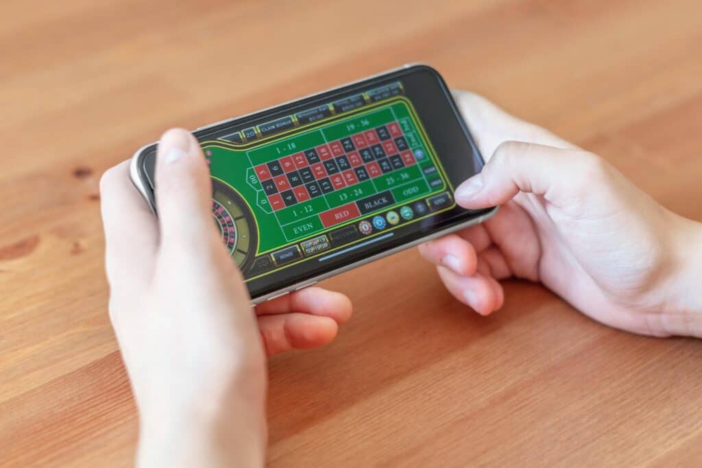 Hands holding a phone showing a roulette game.