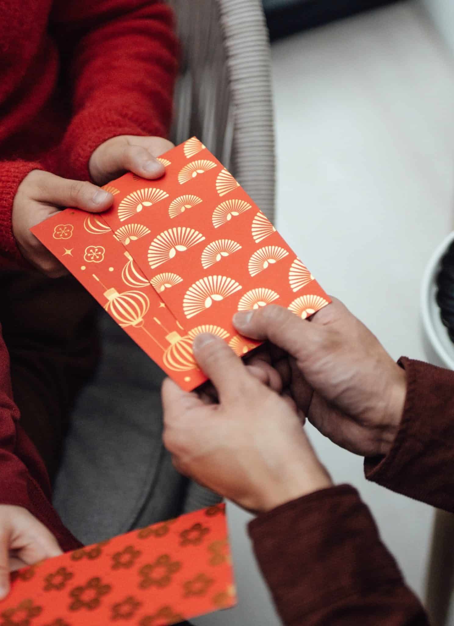 Red and orange Lunar New Year envelope being given to family.