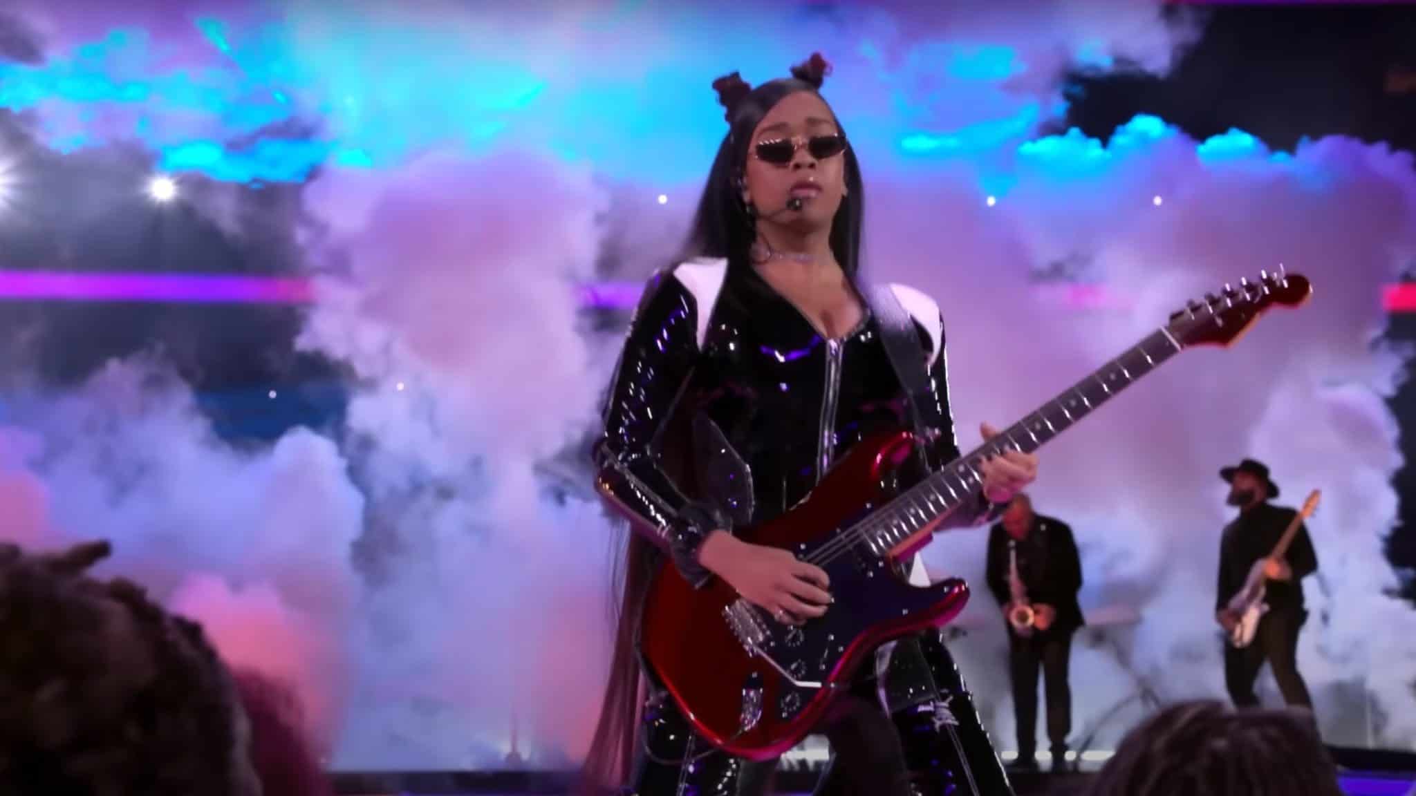 H.E.R. shredding on guitar at Super Bowl with smoke behind her.