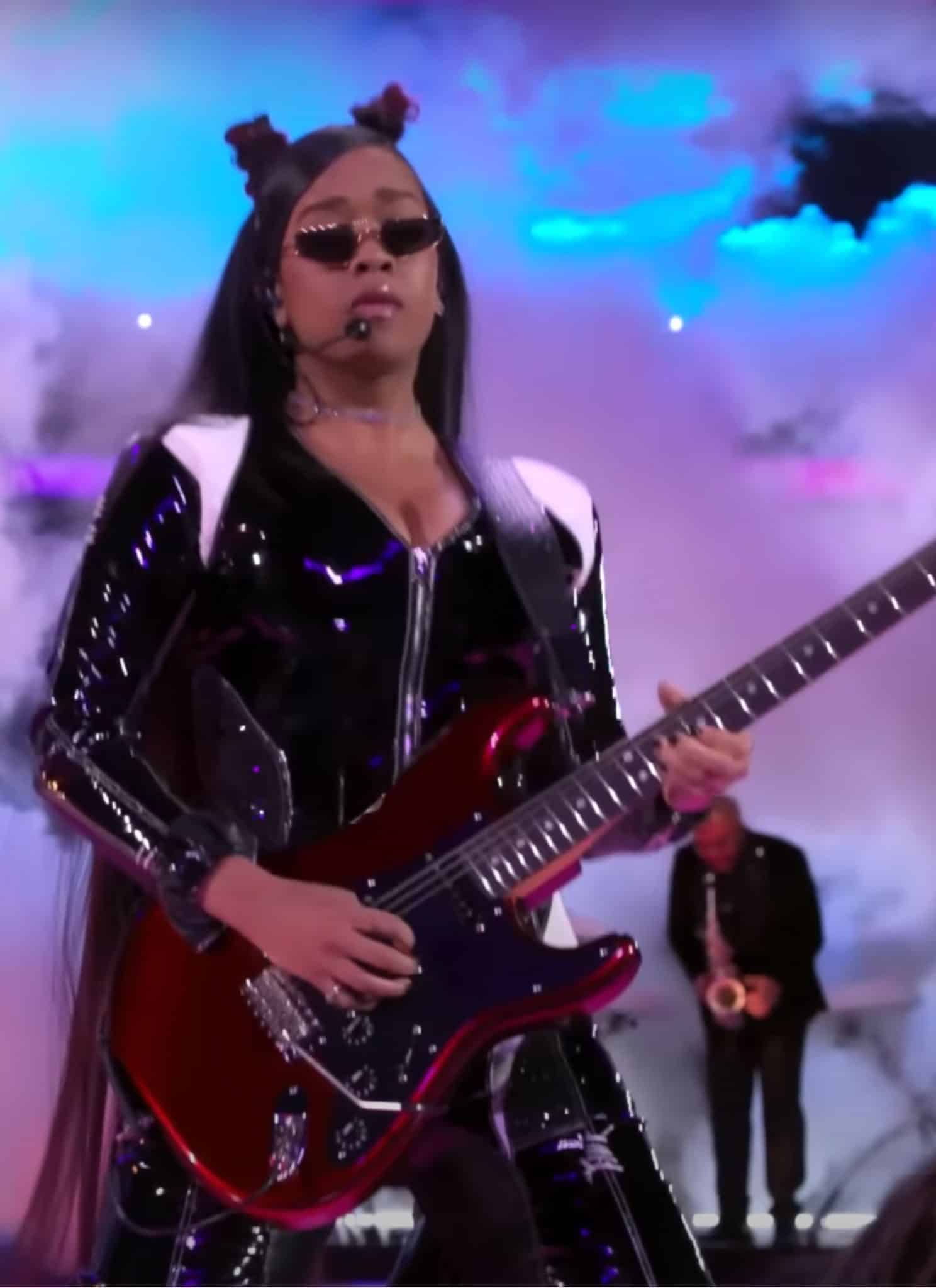 H.E.R. shredding on guitar at Super Bowl with smoke behind her.