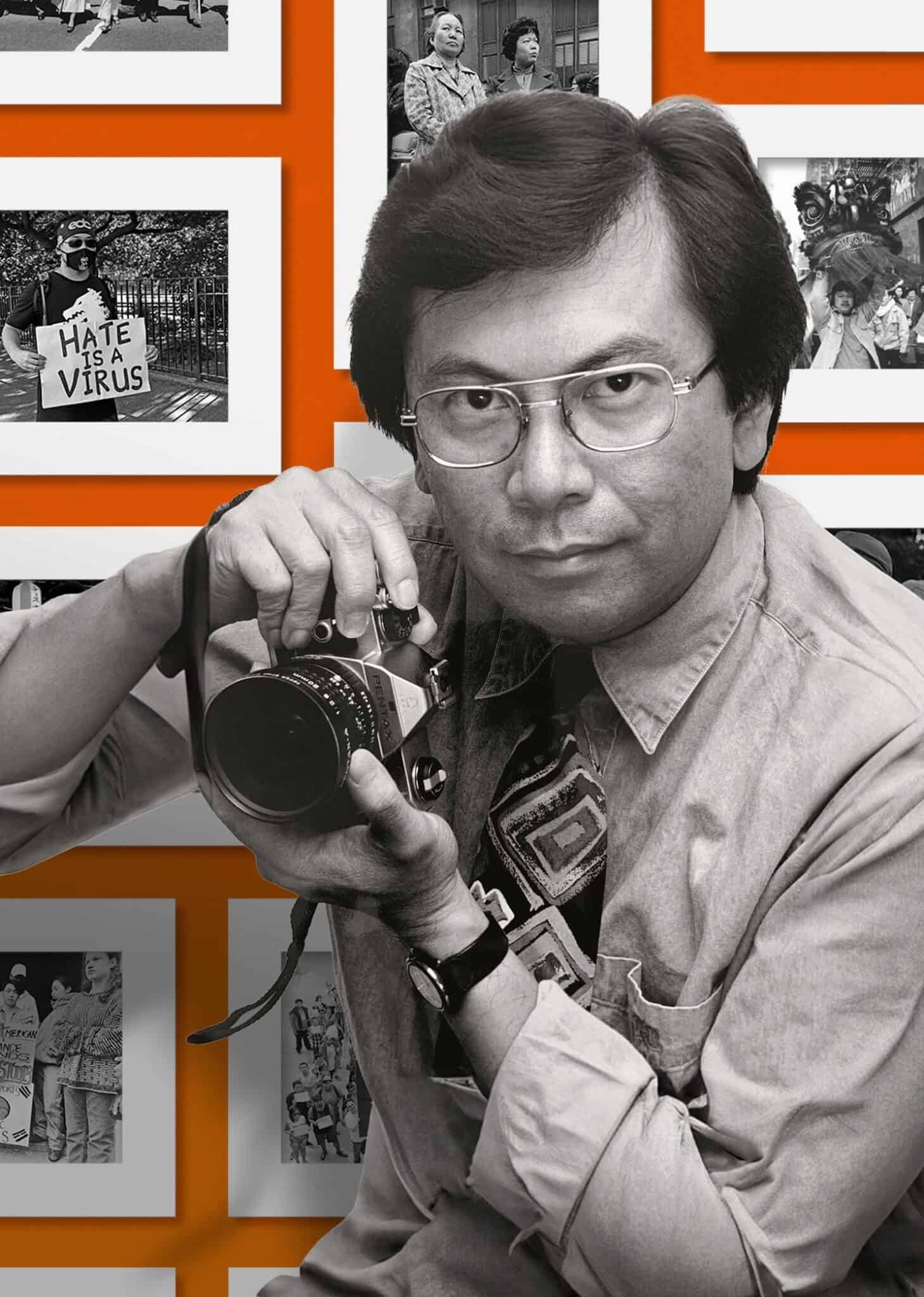 Activist and photojournalist Corky Lee holds a camera, ready to take a photo, against an orange backdrop with black and white photos framed in white.