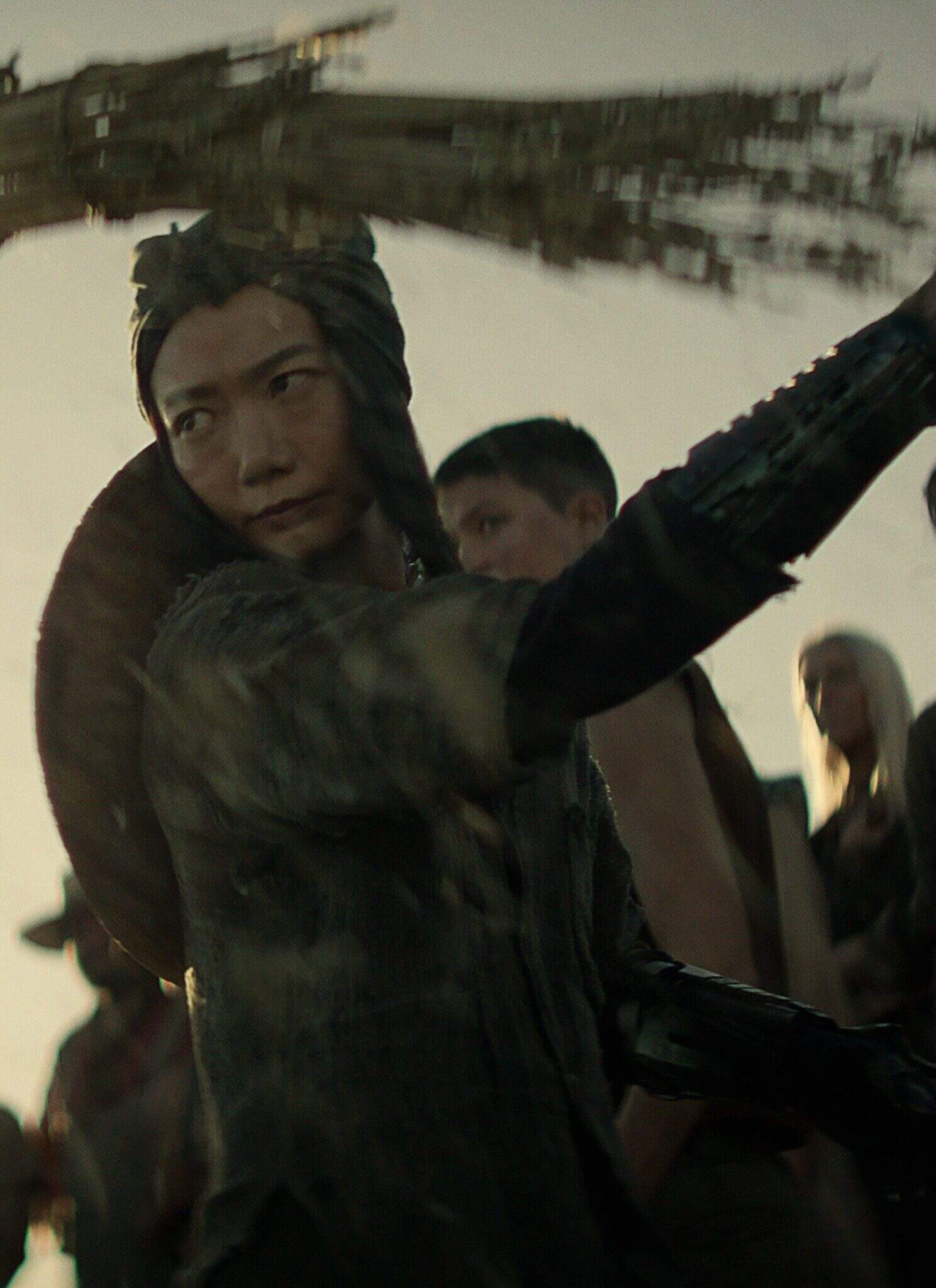 Doona Bae as Nemesis in "Rebel Moon — Part Two: The Scargiver," with other people in the background.