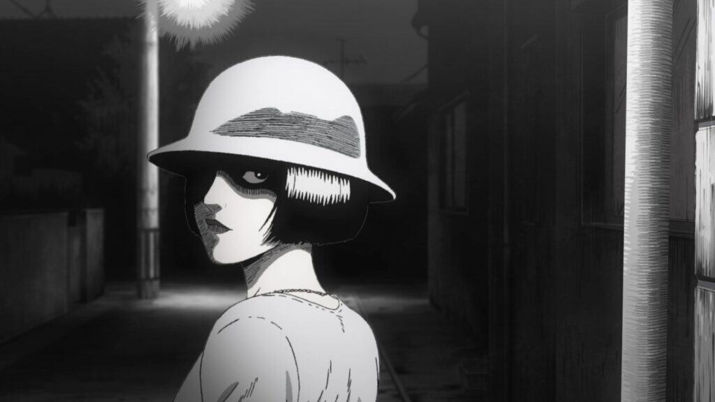 Still frame from "Uzumaki." A woman in a hat stands in a dark alley.