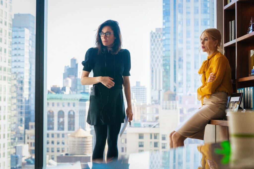 Still frame from "Babygirl." Two women in an office look off-screen at something.