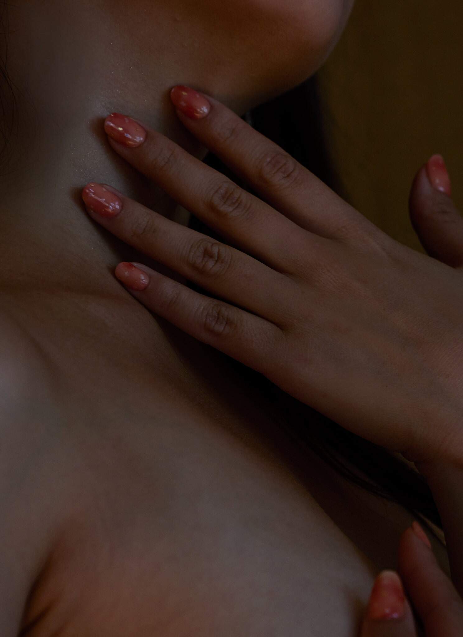 A woman touches her own neck sensually.