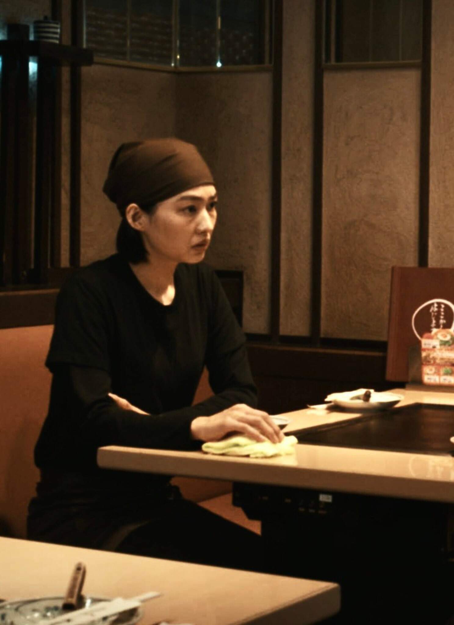 Still from "The Longing"; two people sit across from each other at a table.