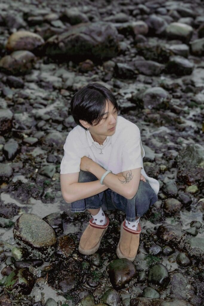 yung kai squatting outside.