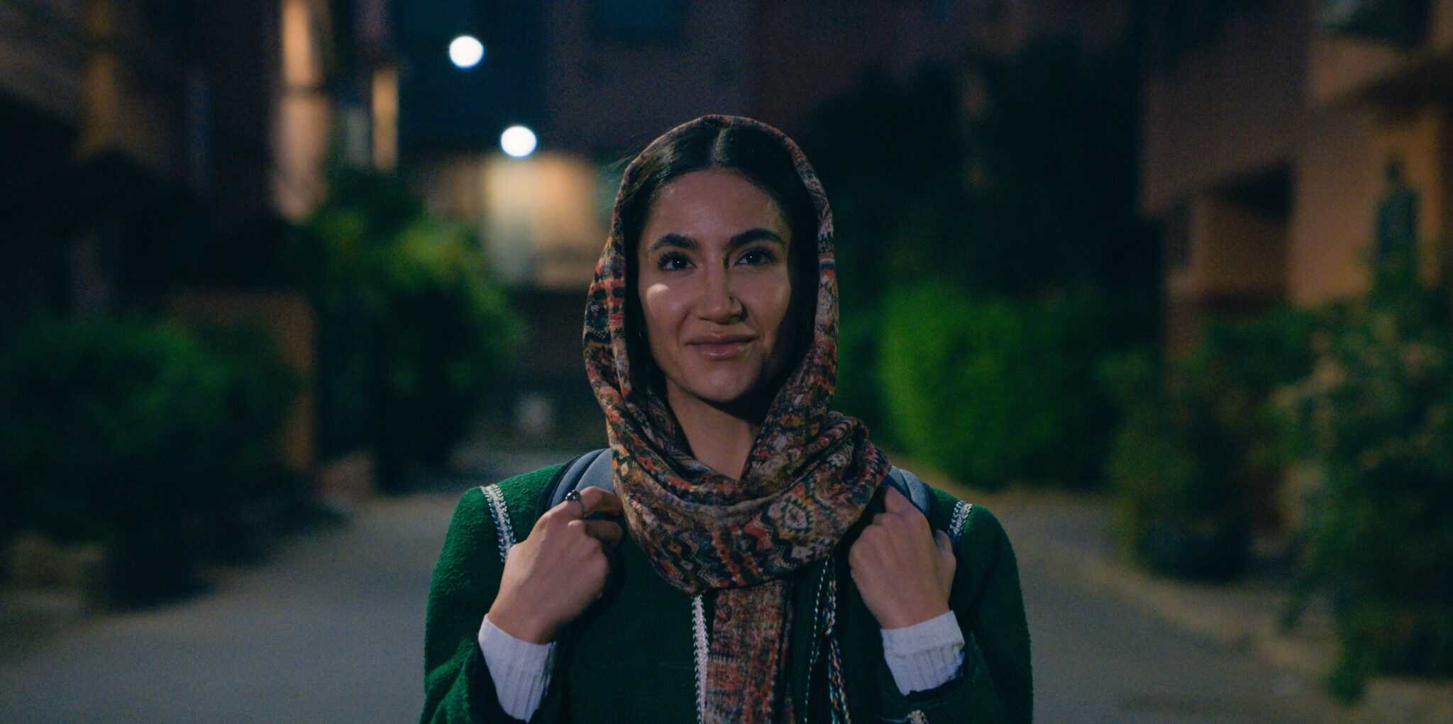 A woman stands and stares at the camera.