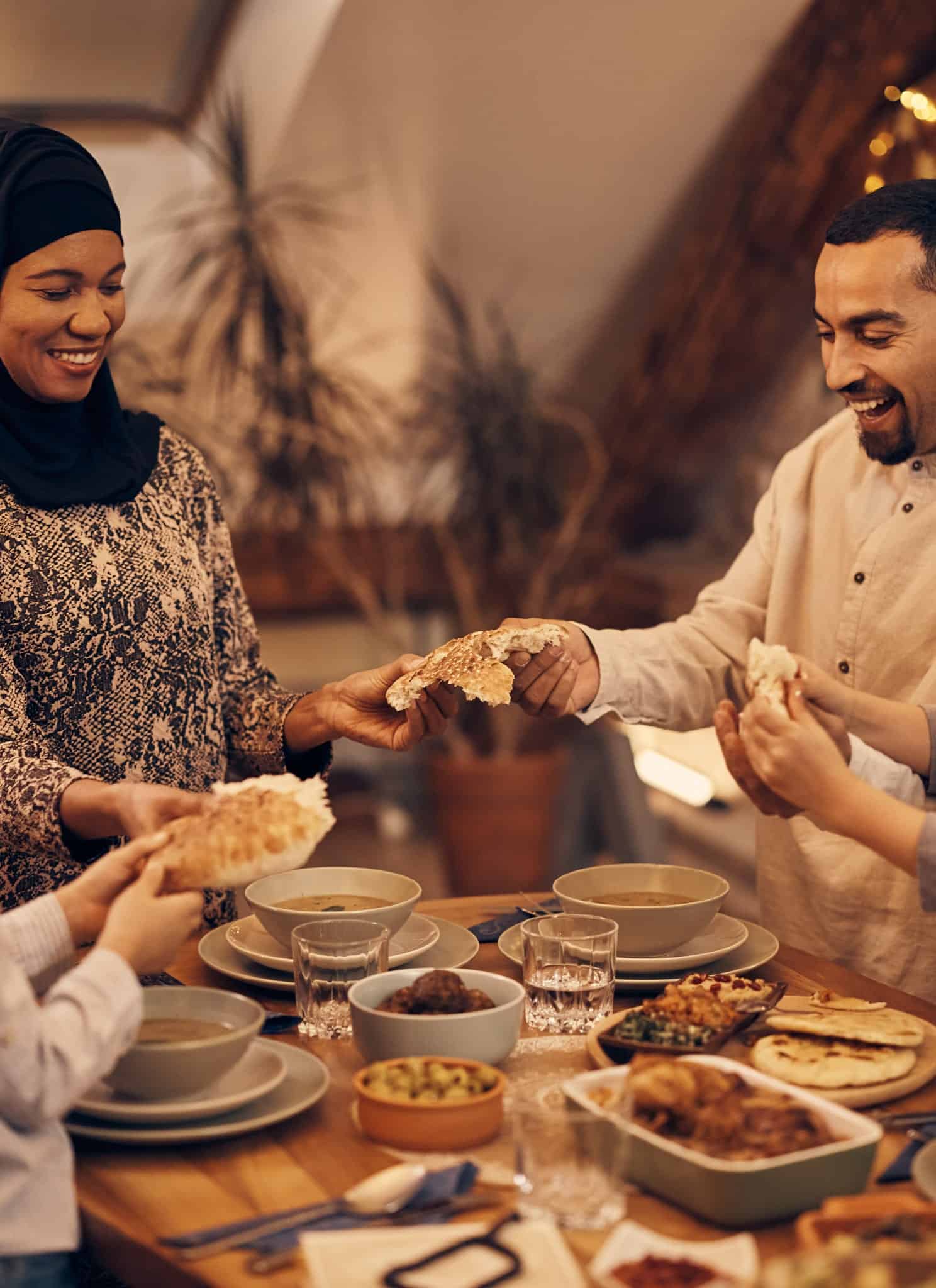 Happy Muslim parents and their kids sharing pita bread.