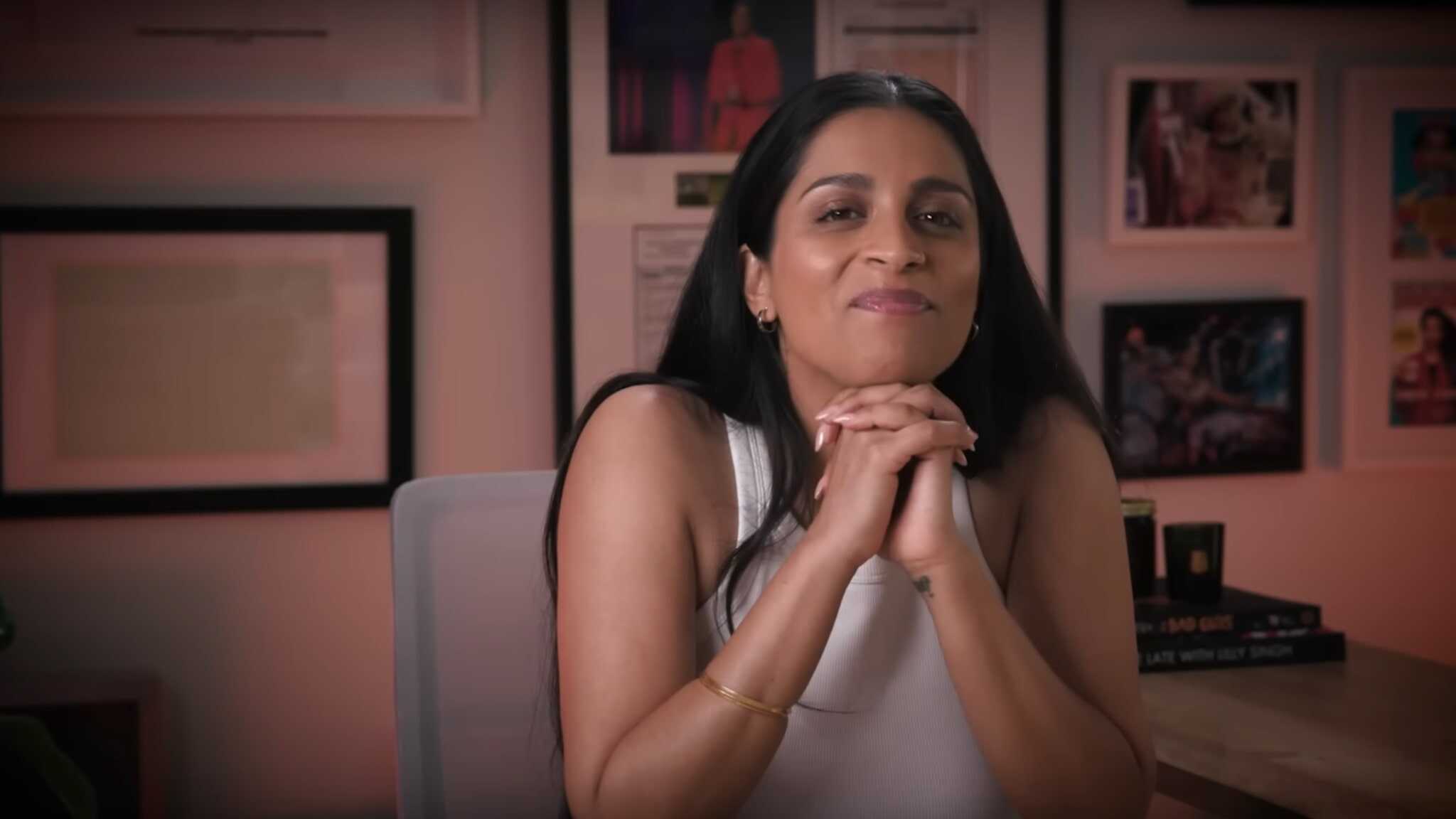 Lilly Singh in white top sitting at her desk.
