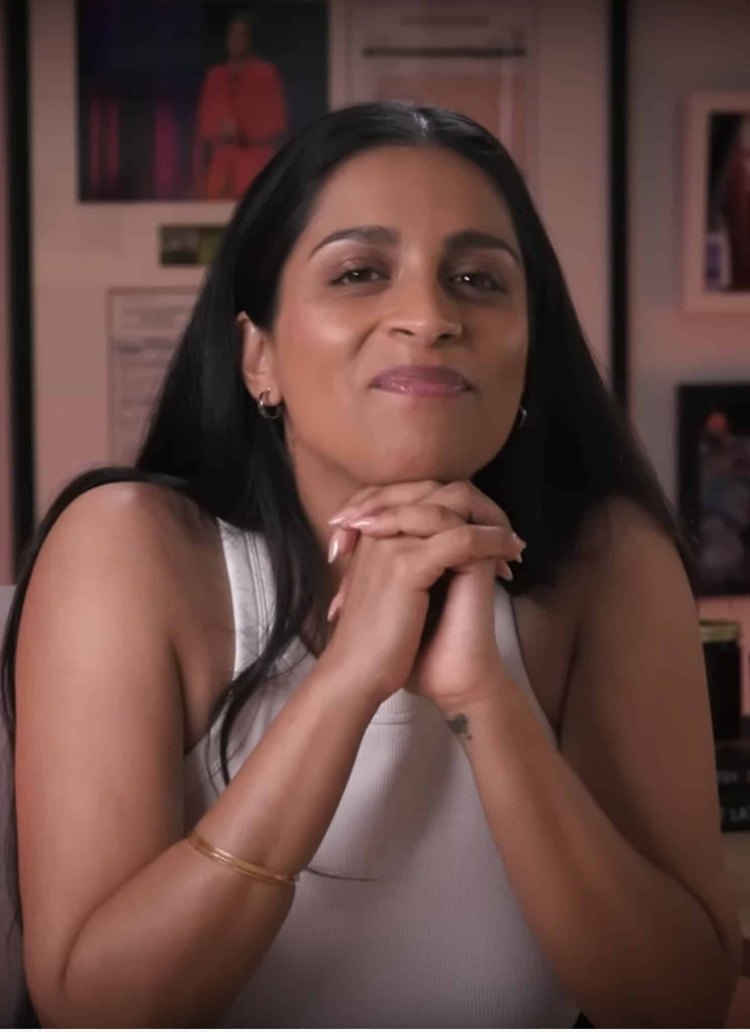Lilly Singh in white top sitting at her desk.