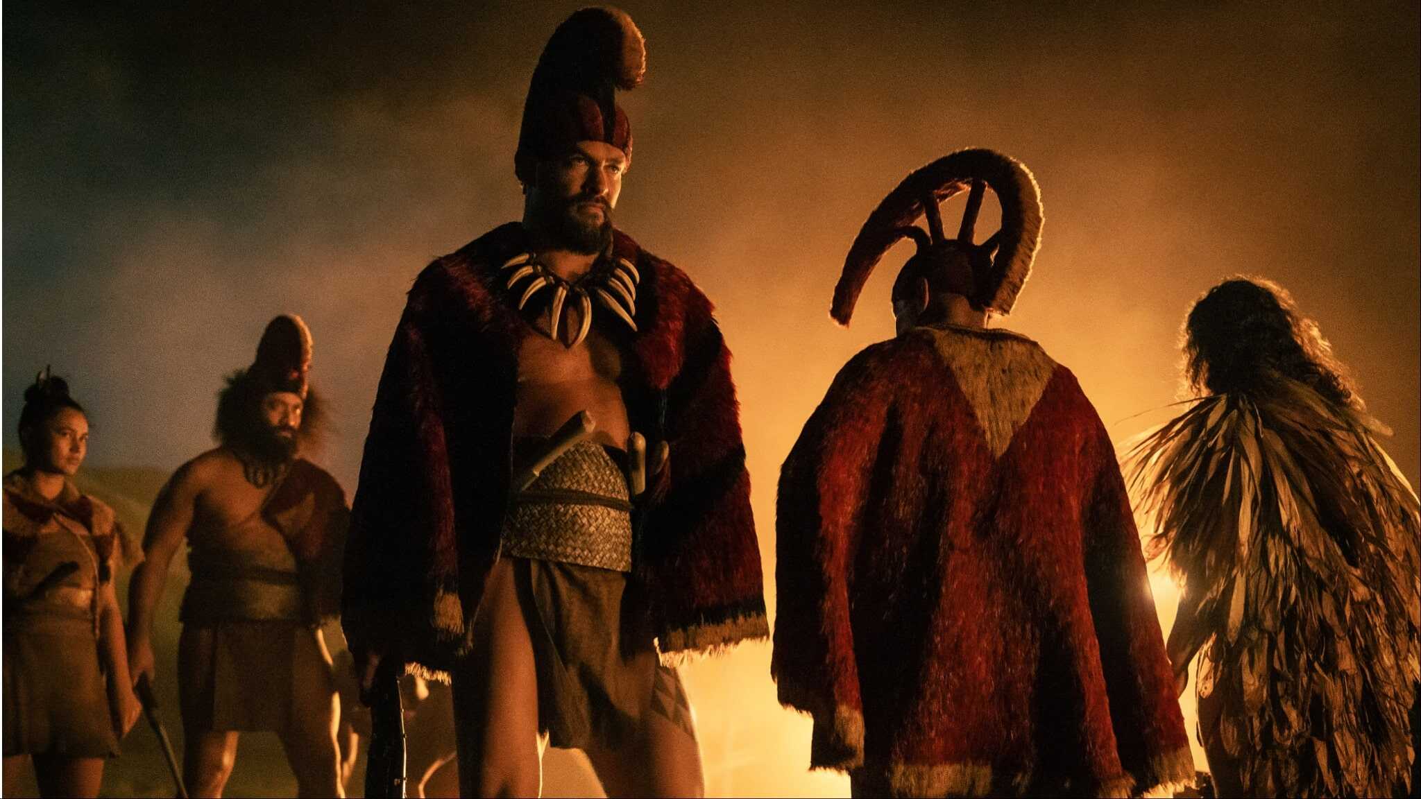 Jason Momoa standing in Polynesian clothing with other warriors.