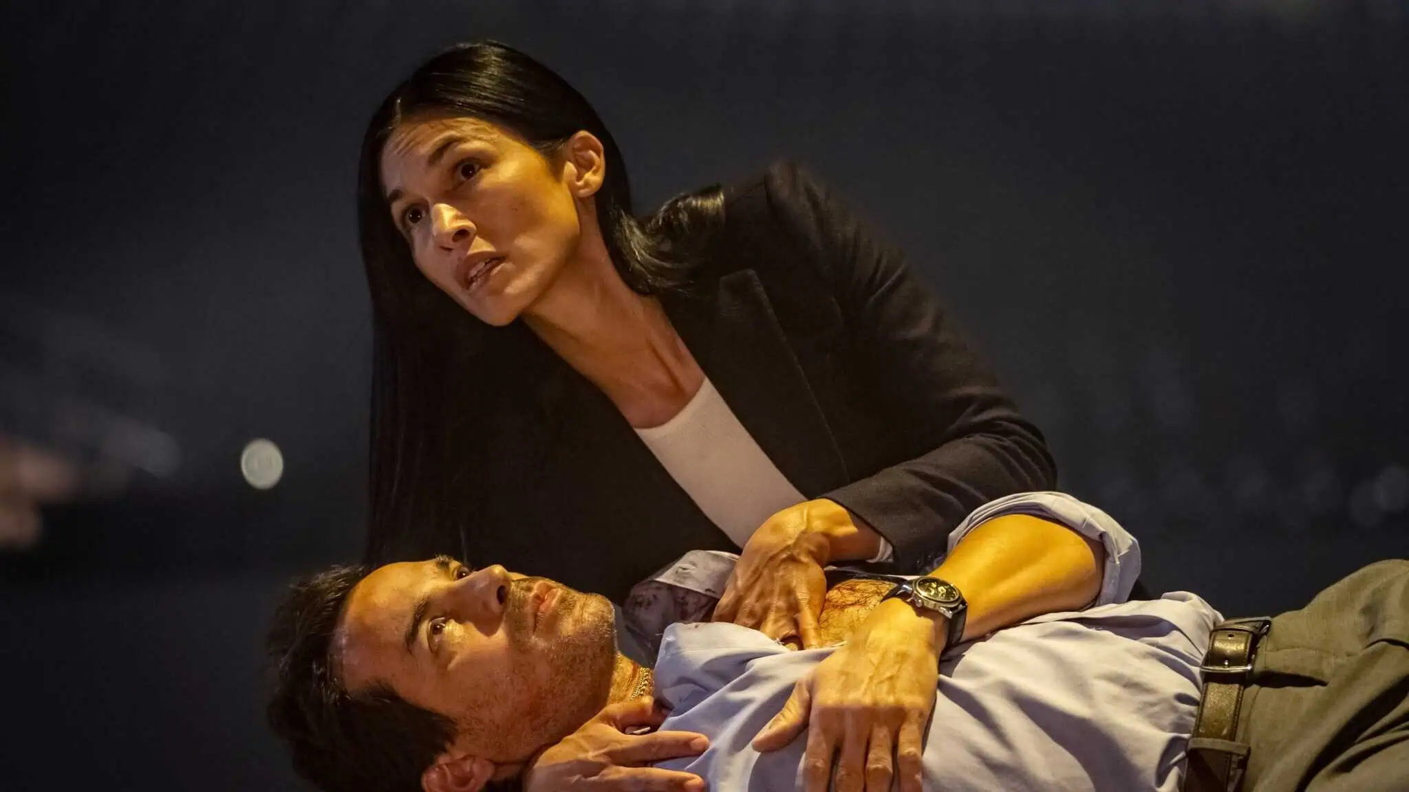 Actor Santiago Cabrera lays on the ground while actor Élodie Yung holds him in the "The Cleaning Lady."