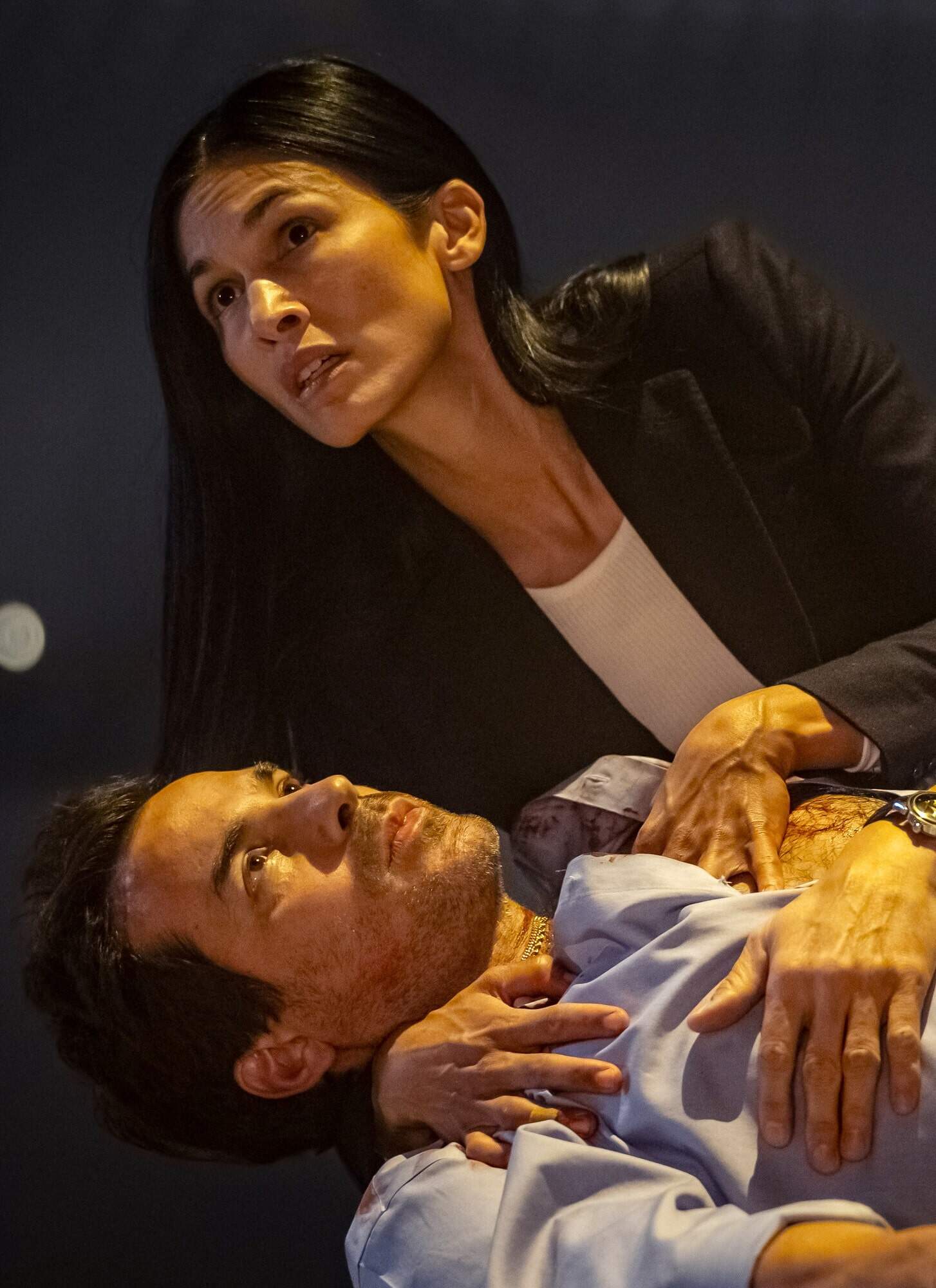 Actor Santiago Cabrera lays on the ground while actor Élodie Yung holds him in the "The Cleaning Lady."