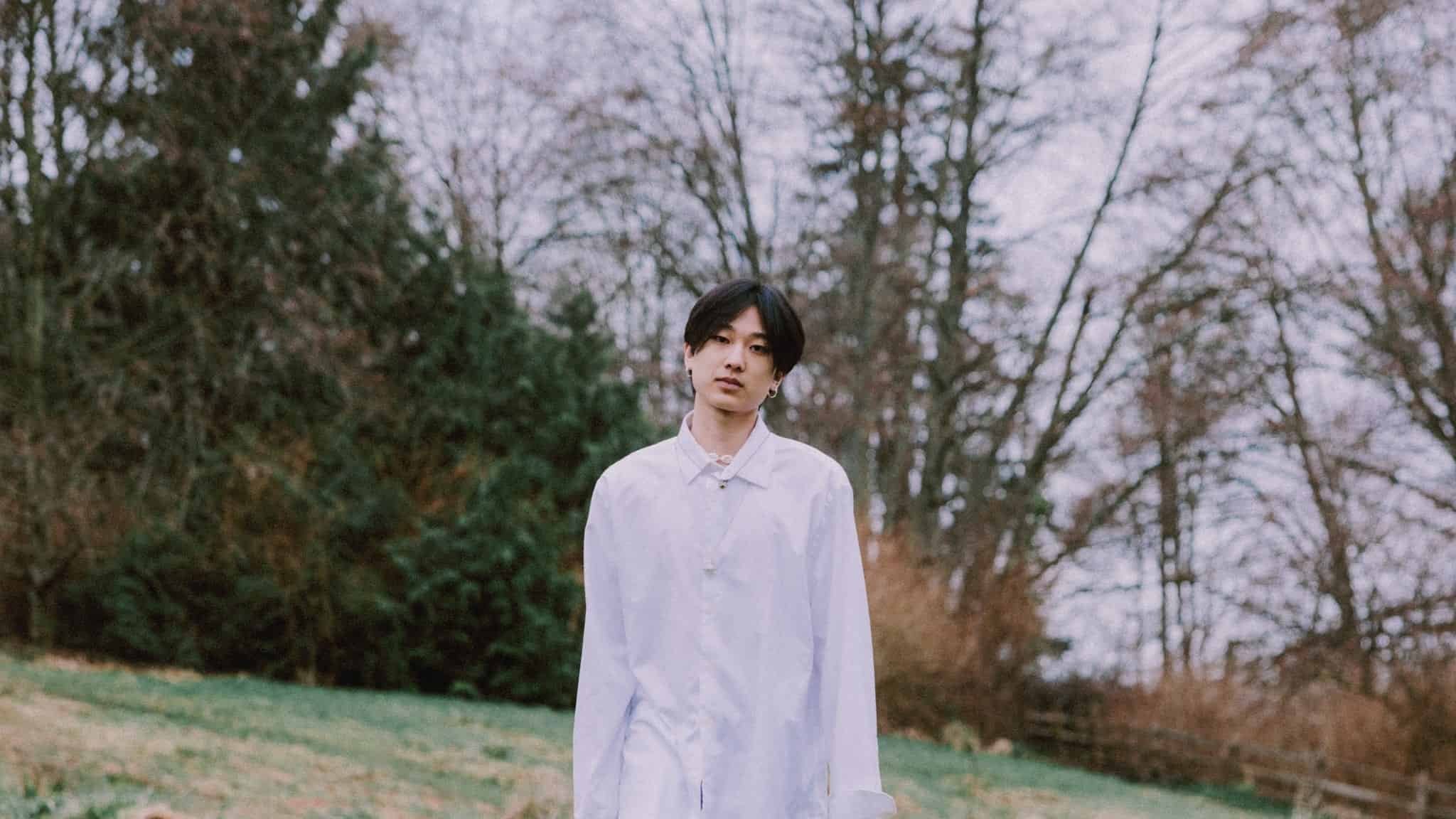 Yung Kai standing in nature.