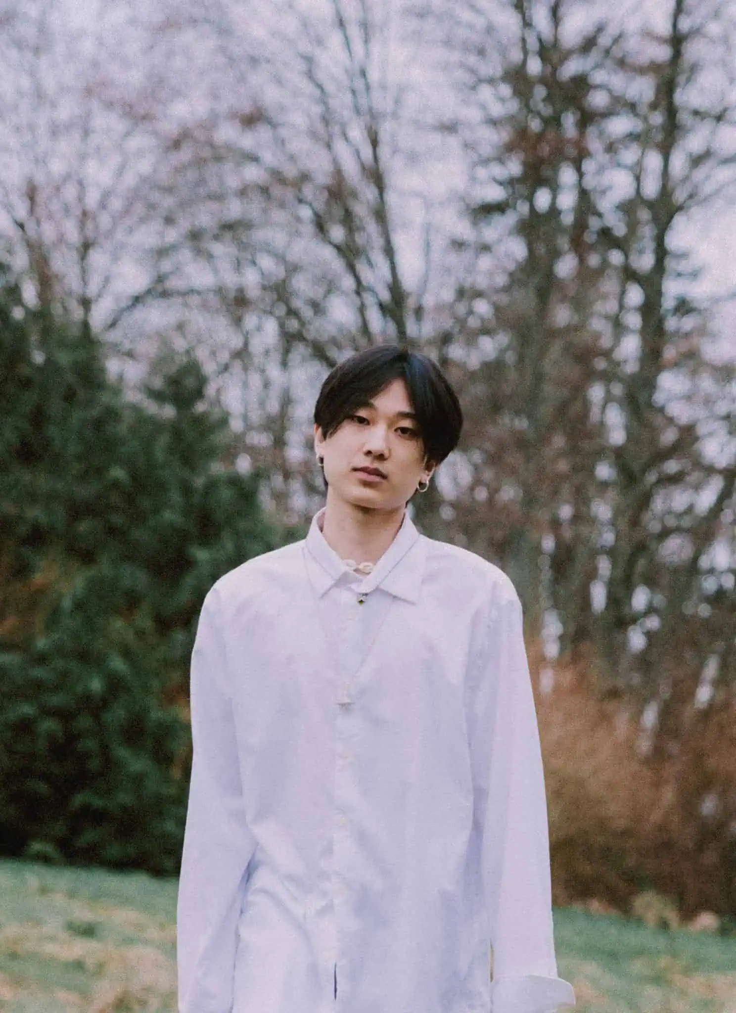 Yung Kai standing in nature.