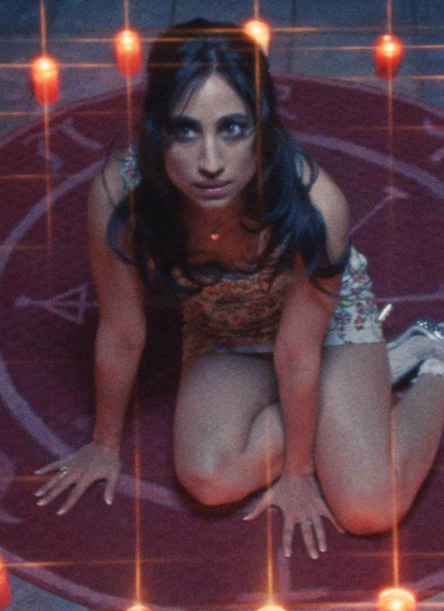 Still from FToys; a woman sits in a circle of candles.
