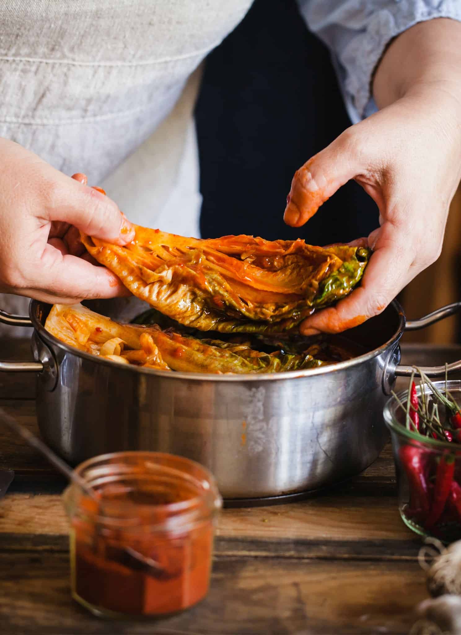 Some placing kimchi into a pot.
