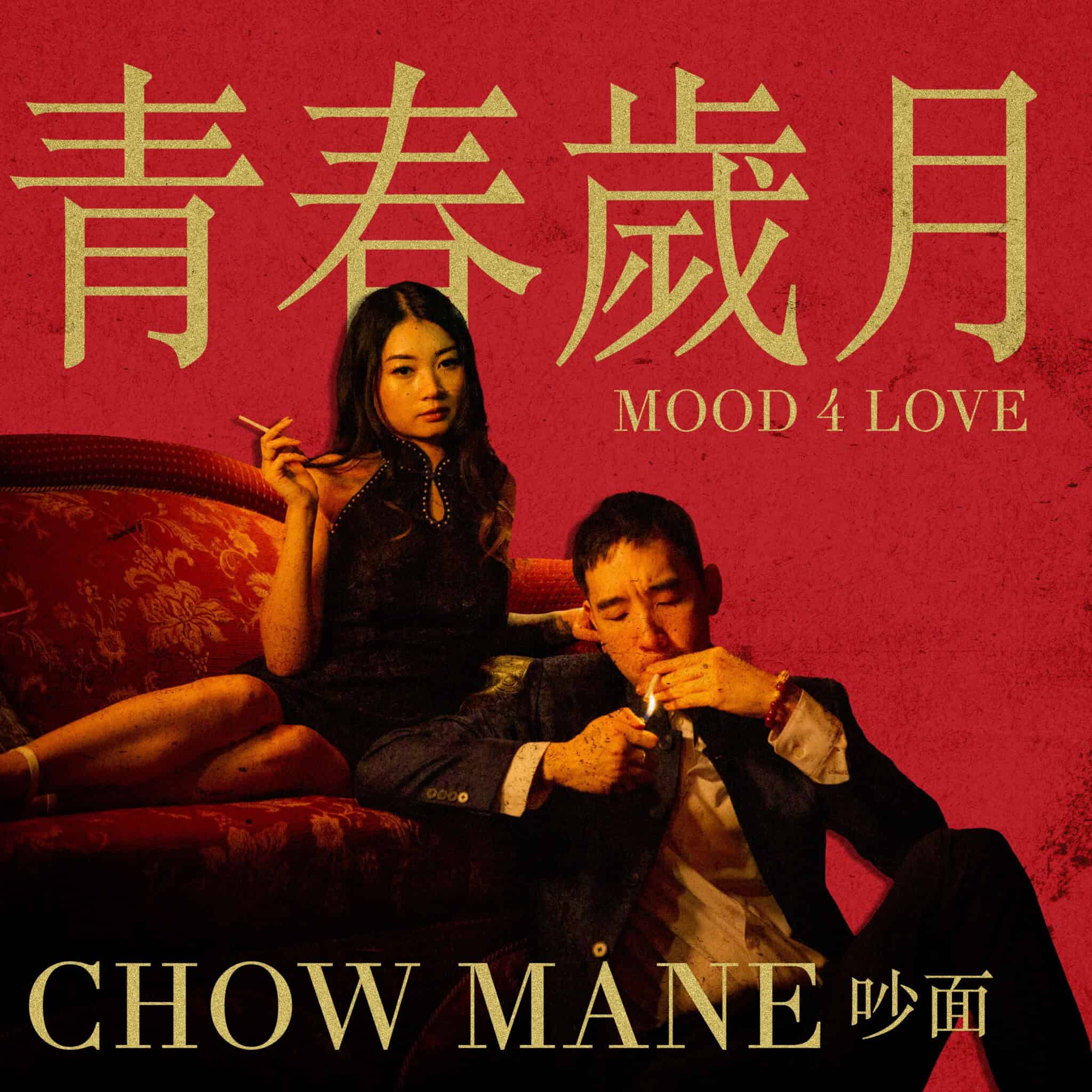 An Asian woman sits on a red couch with a cigarette in hand as an Asian man sits in front of her lighting a cigarette, against a red background.