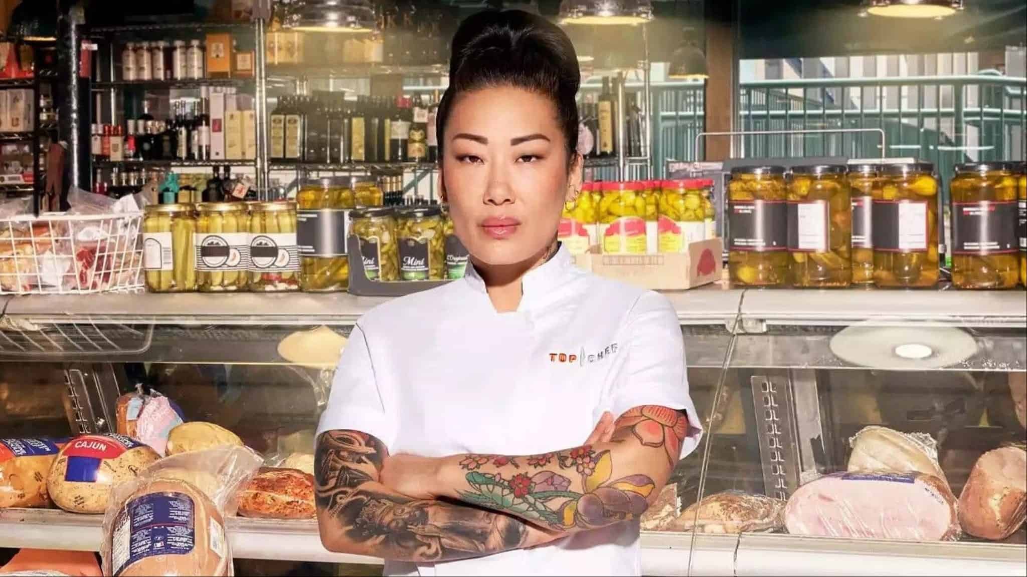Katianna Hong in white chef jacket standing in front of deli counter.