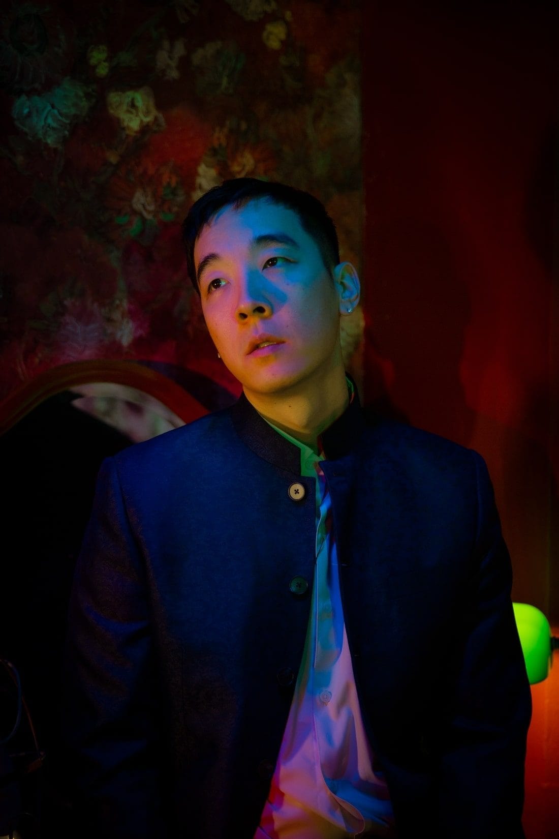 Chinese American rapper Chow Mane, dressed in a dark Chinese-style jacket in a "In the Mood for Love" styled room