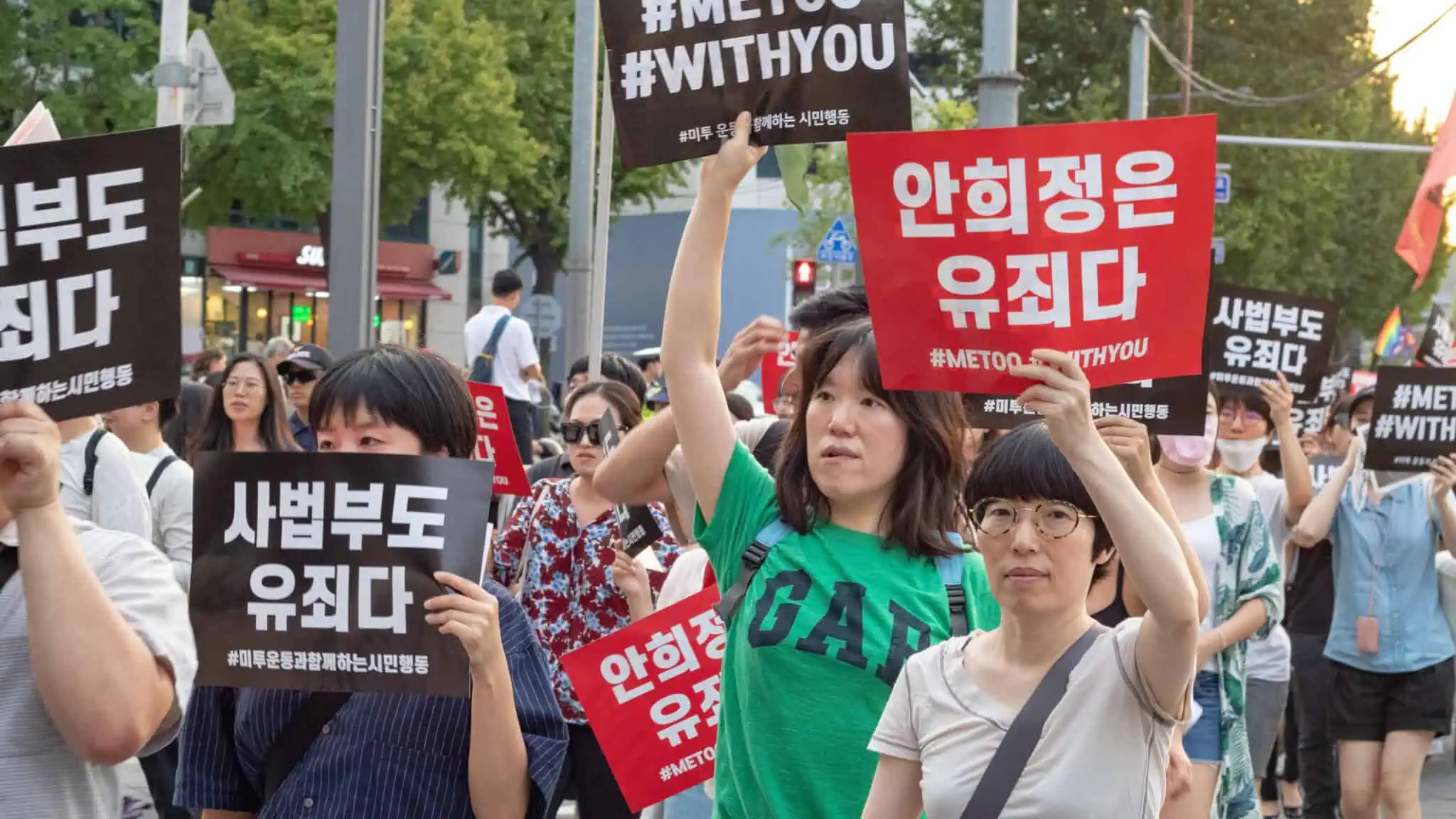 South Korean women hold up signs in Korean at a protest demonstration.