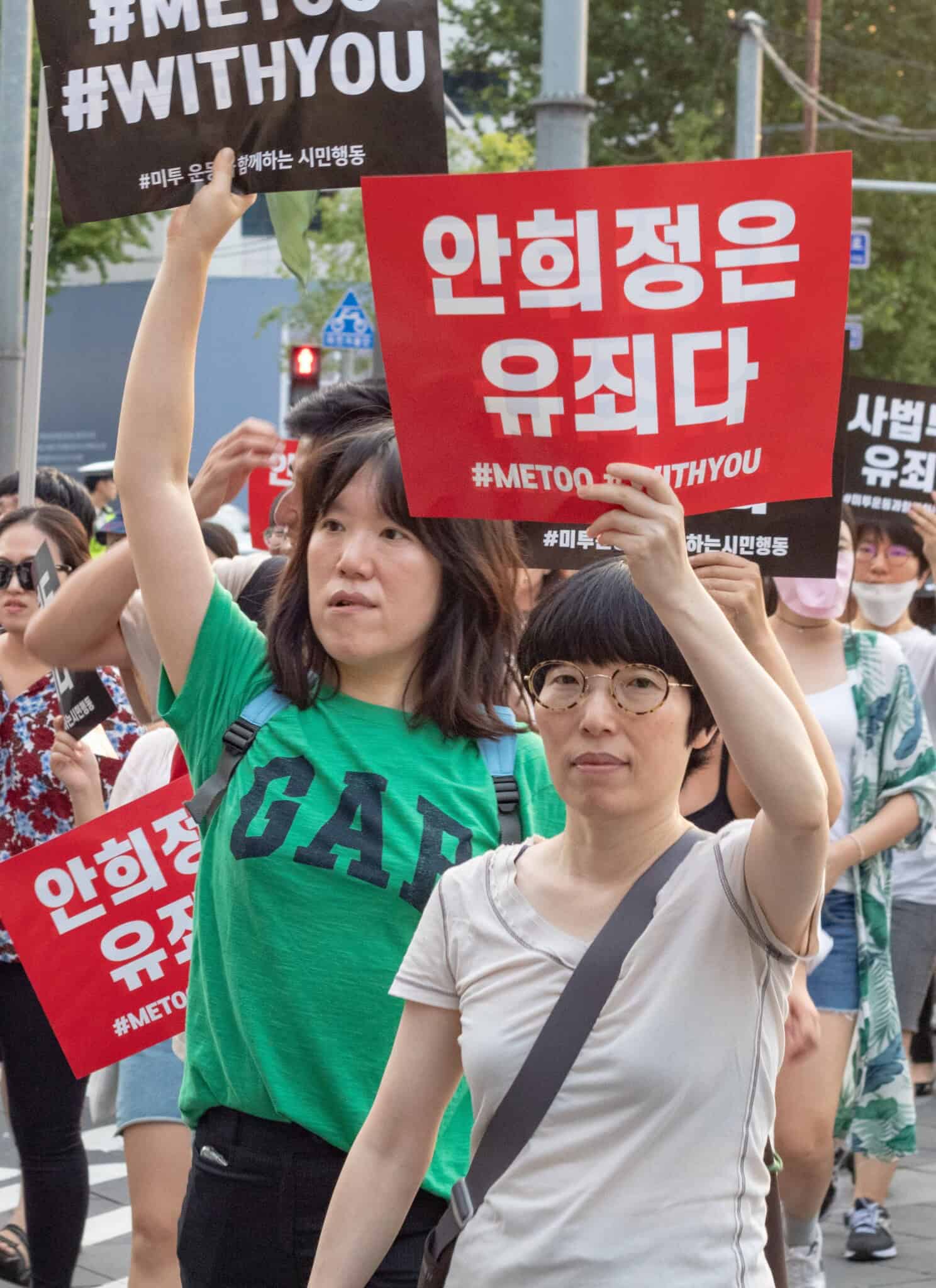South Korean women hold up signs in Korean at a protest demonstration.