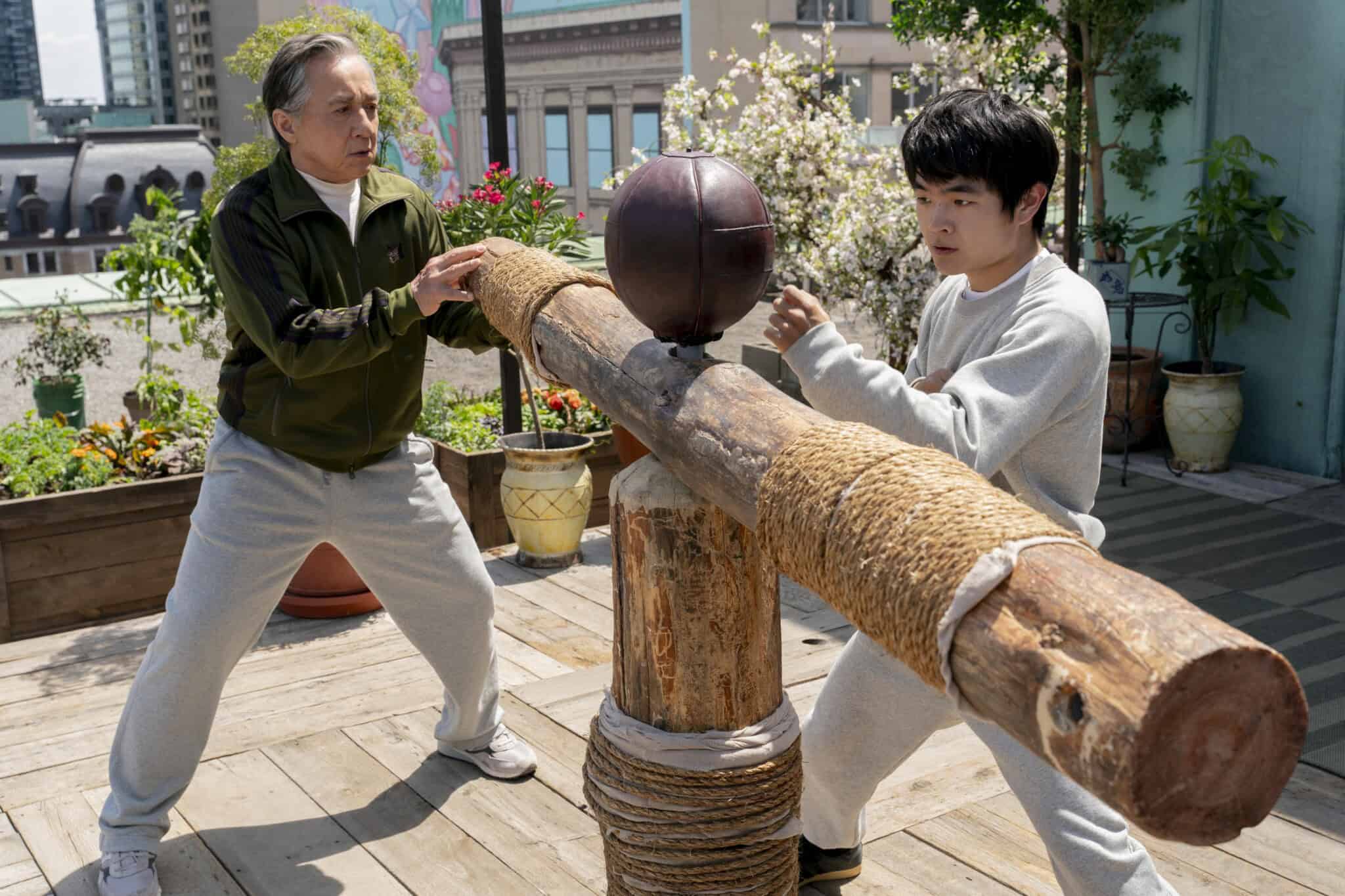 Actors Jackie Chan and Ben Wang stand at piece of wooden martial arts training equipment in "Karate Kid: Legends."
