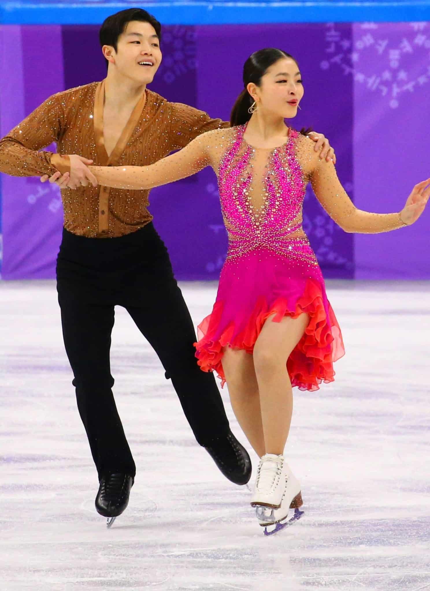 Alex and Maia Shibutani figure skating on ice in brown and pink outfit.