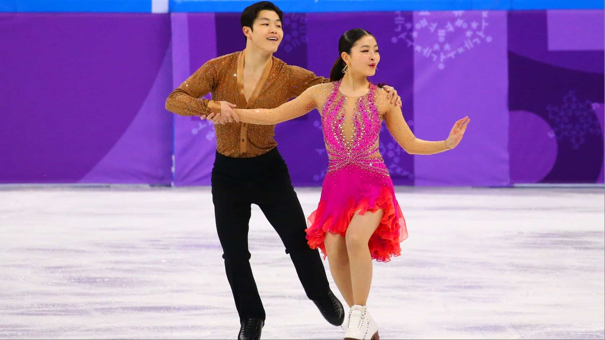 Alex and Maia Shibutani figure skating on ice in brown and pink outfit.