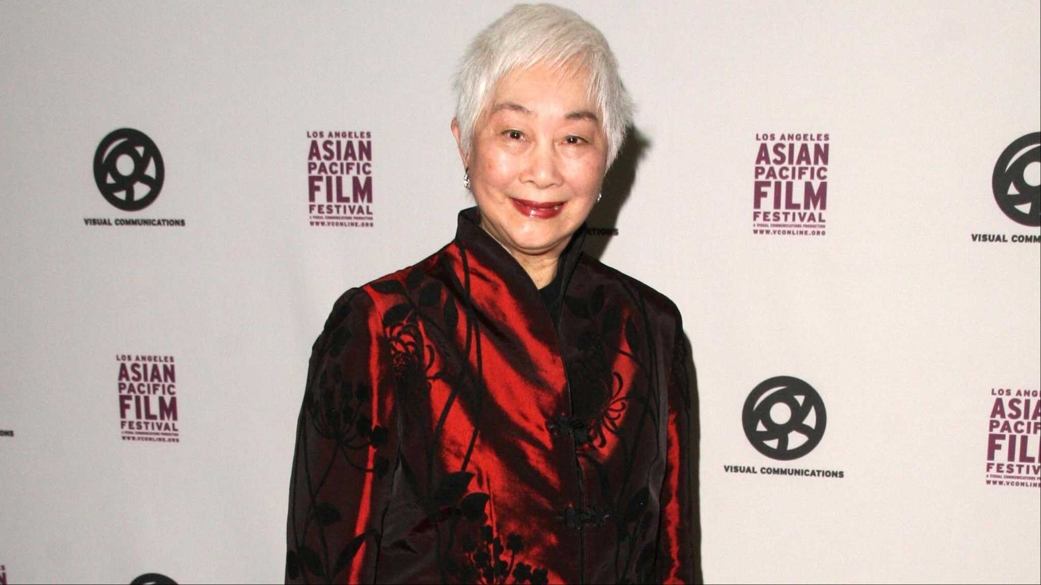 Lisa Lu standing in front of backdrop in red and black outfit.
