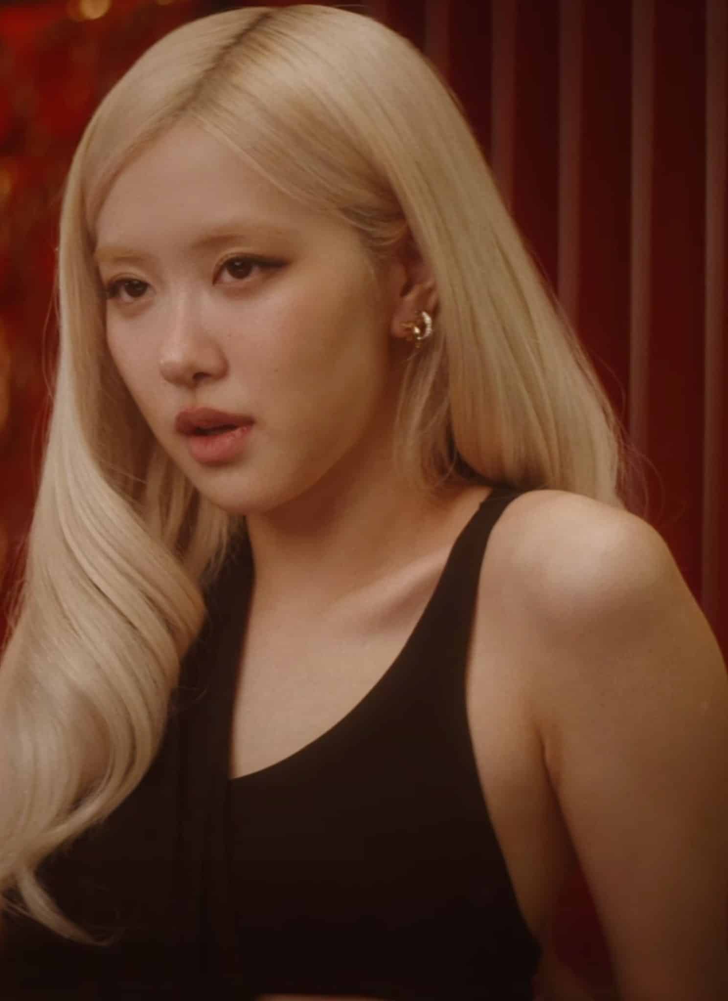 Rosé singing and sitting in red room wearing black top.