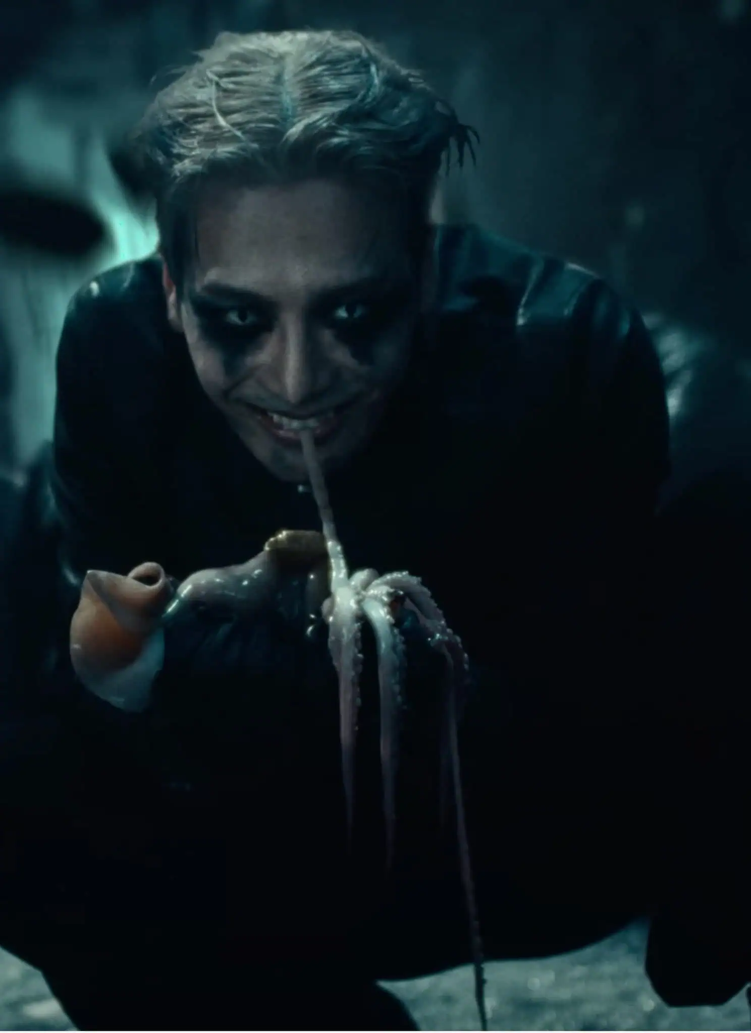 Jackson Wang in Buck music video with tentacle in mouth and squatting.