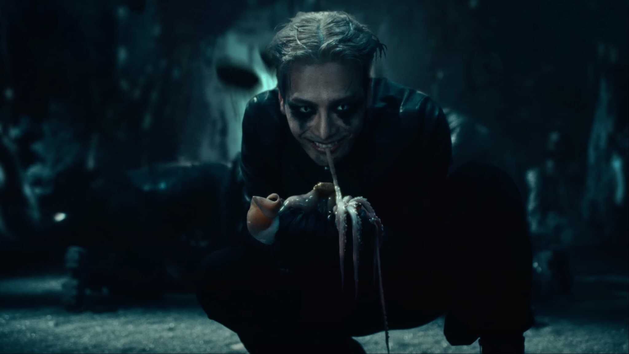 Jackson Wang in Buck music video with tentacle in mouth and squatting.