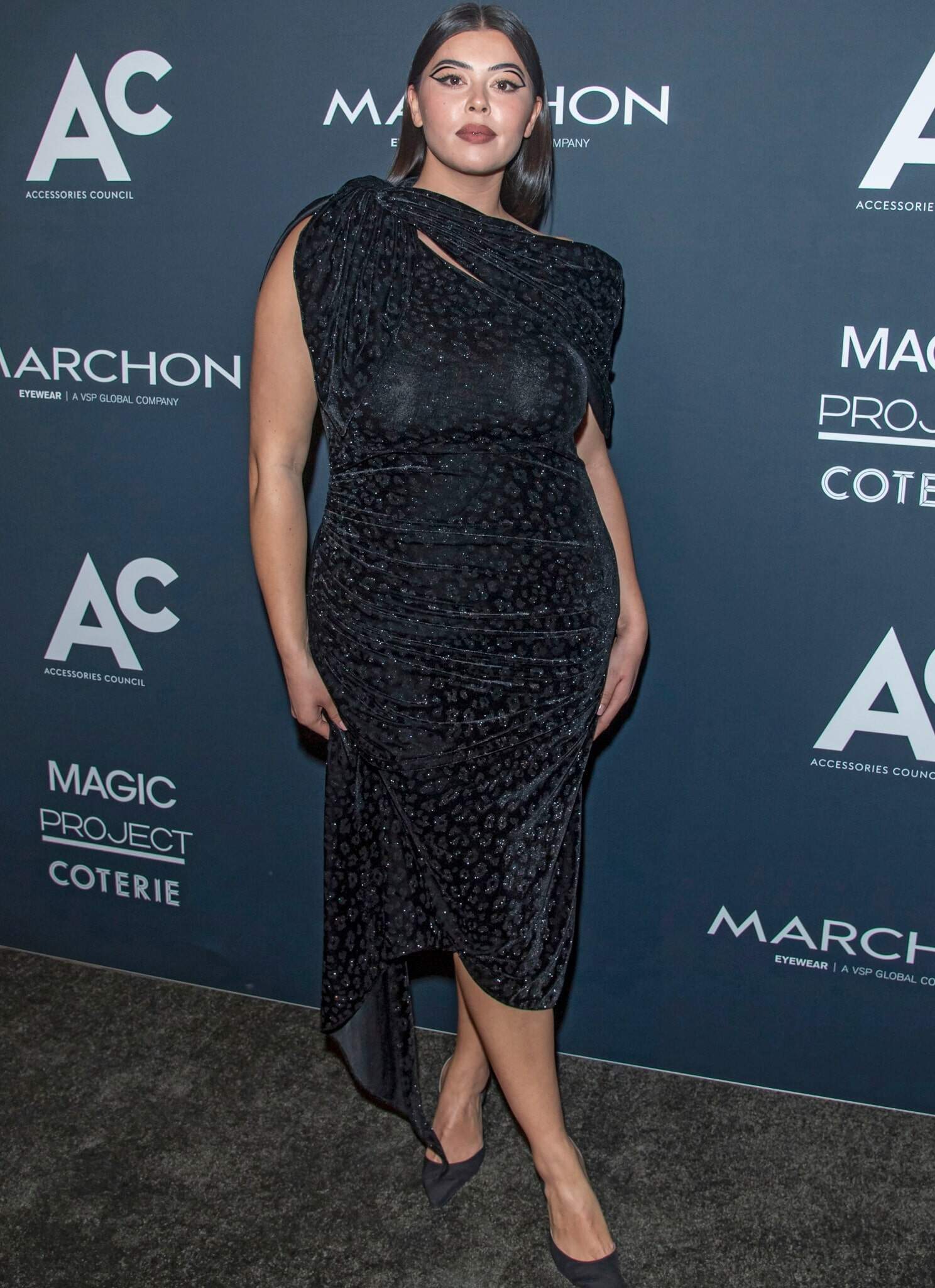 Lauren Chan in blue/black dress standing in front of step and repeat.