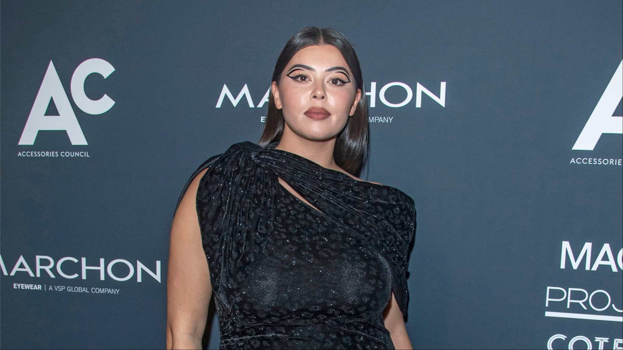 Lauren Chan in blue/black dress standing in front of step and repeat.