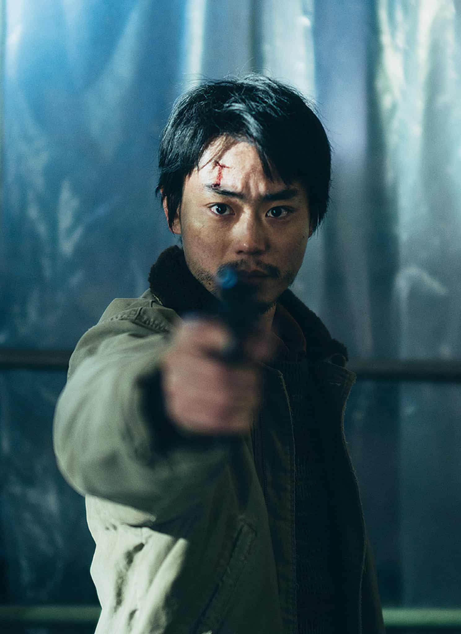 Masaki Suda as Ryosuke Yoshii holding gun wearing green jacket