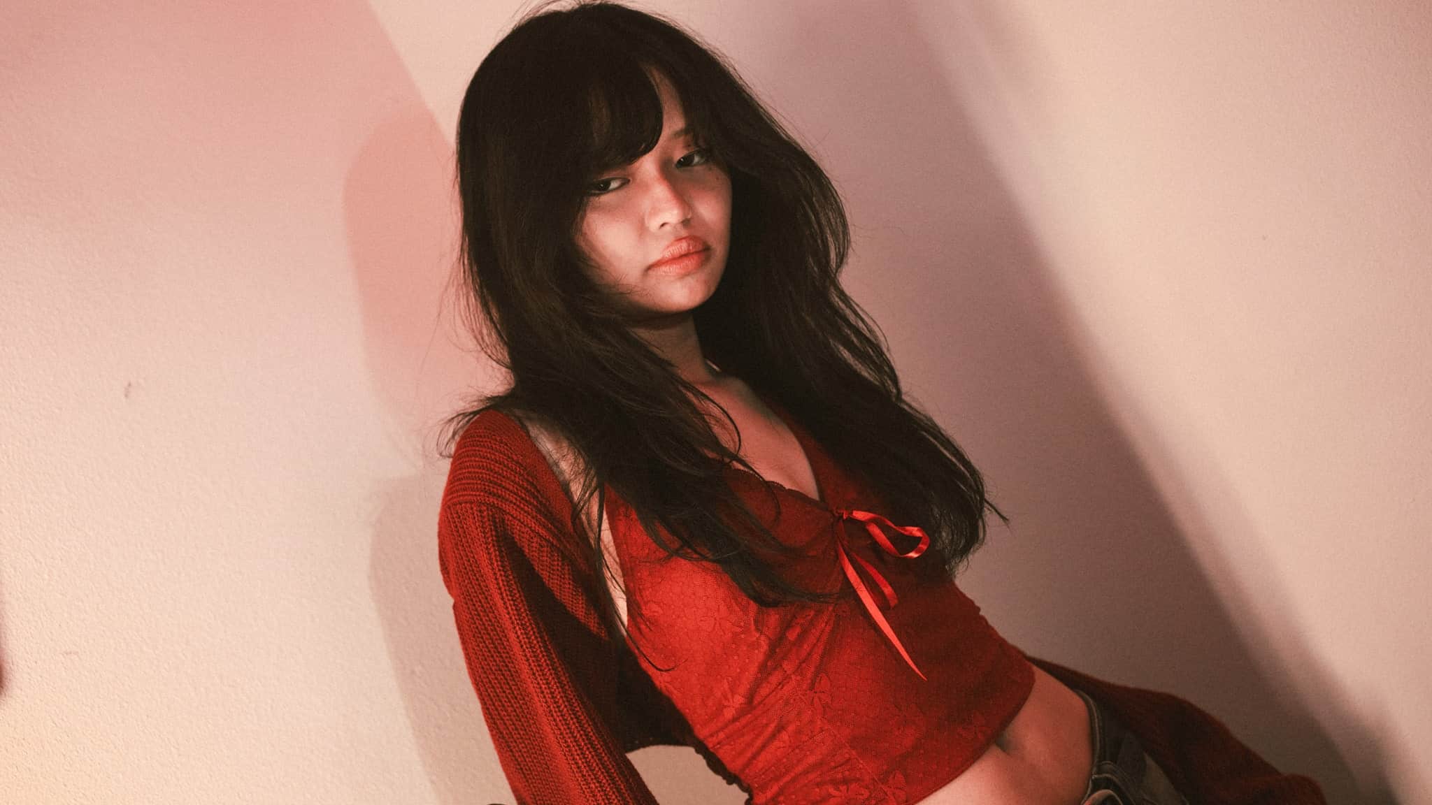 Lyn Lapid wearing a red top in front of a pale ink background.