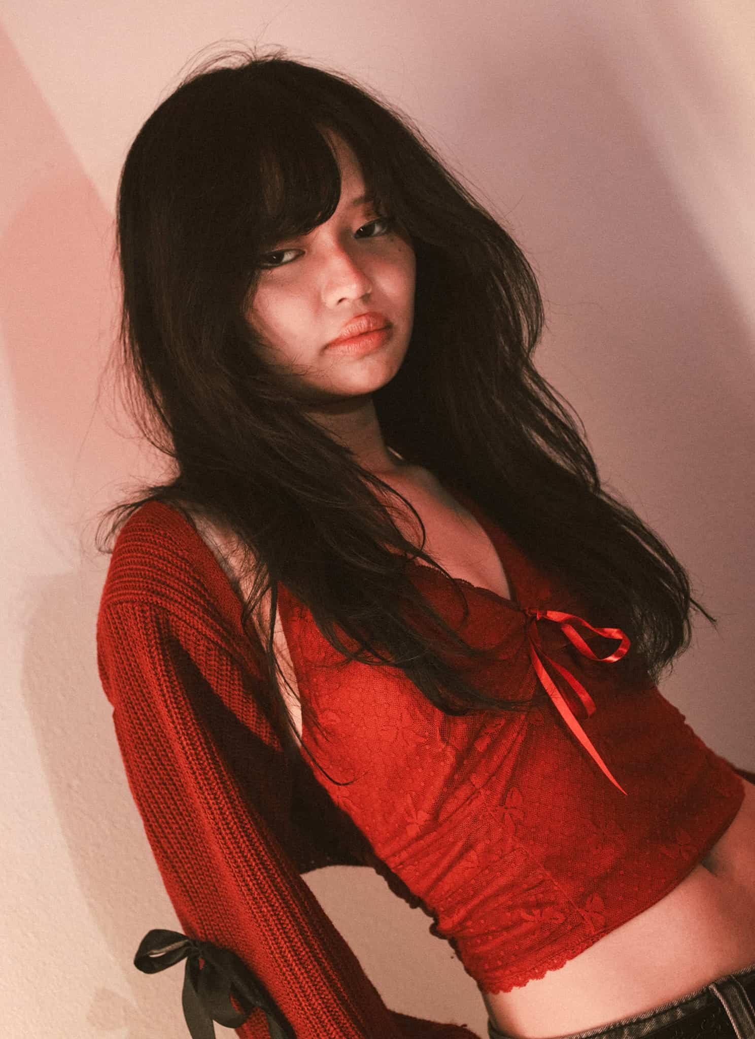 Lyn Lapid wearing a red top in front of a pale ink background.