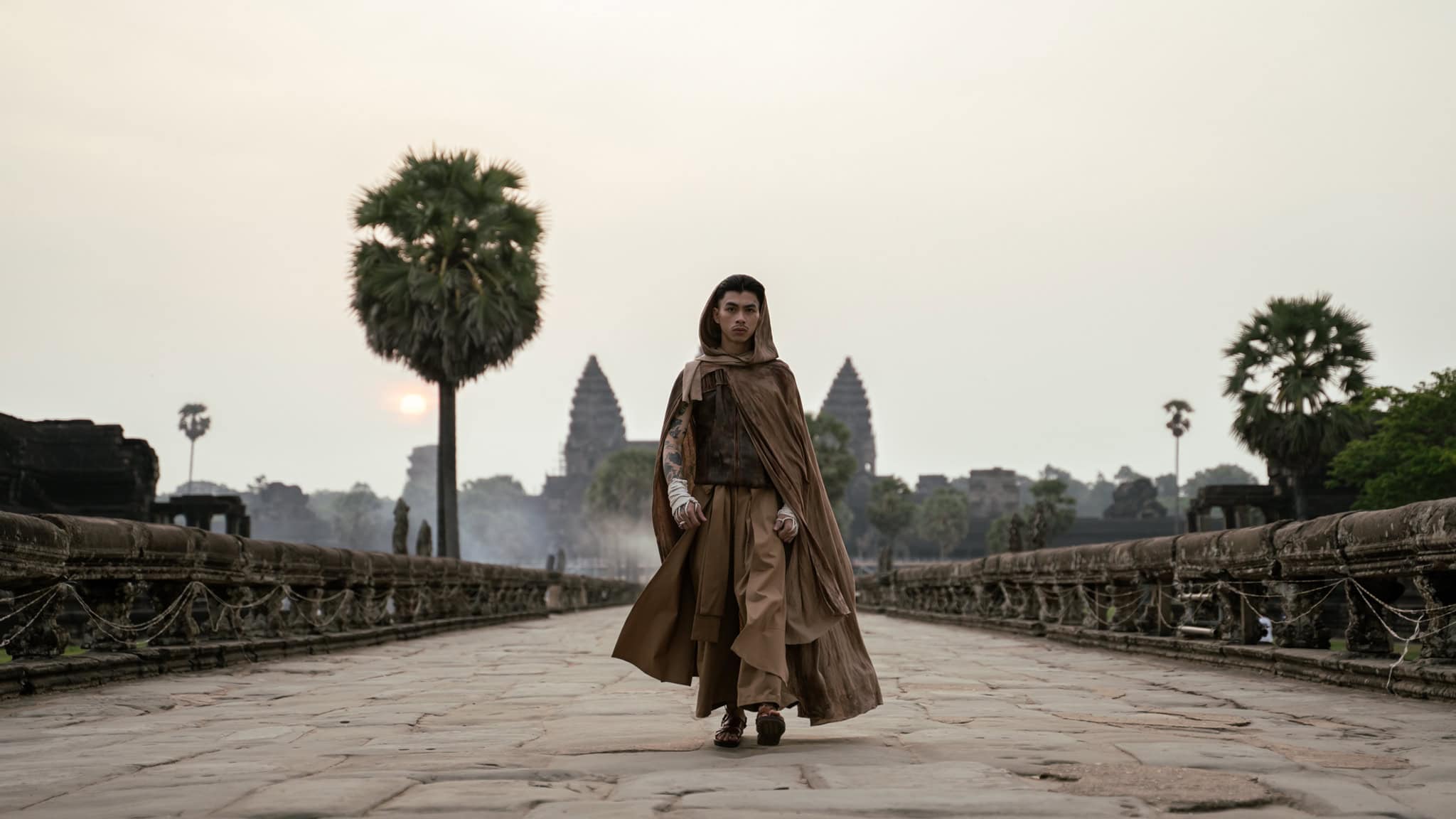 Cambodian rapper VannDa ins a hooded robe, in front of Angkor Wat.