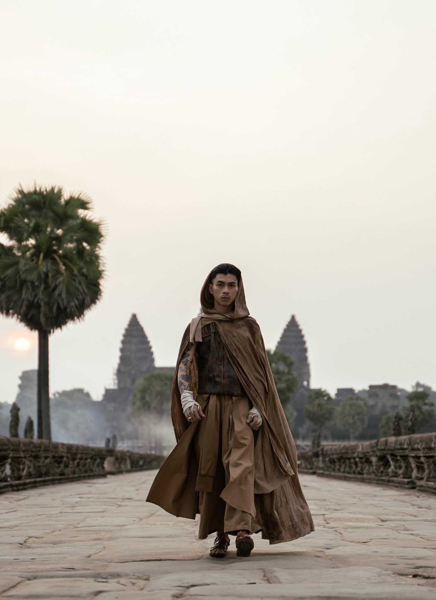 Cambodian rapper VannDa ins a hooded robe, in front of Angkor Wat.