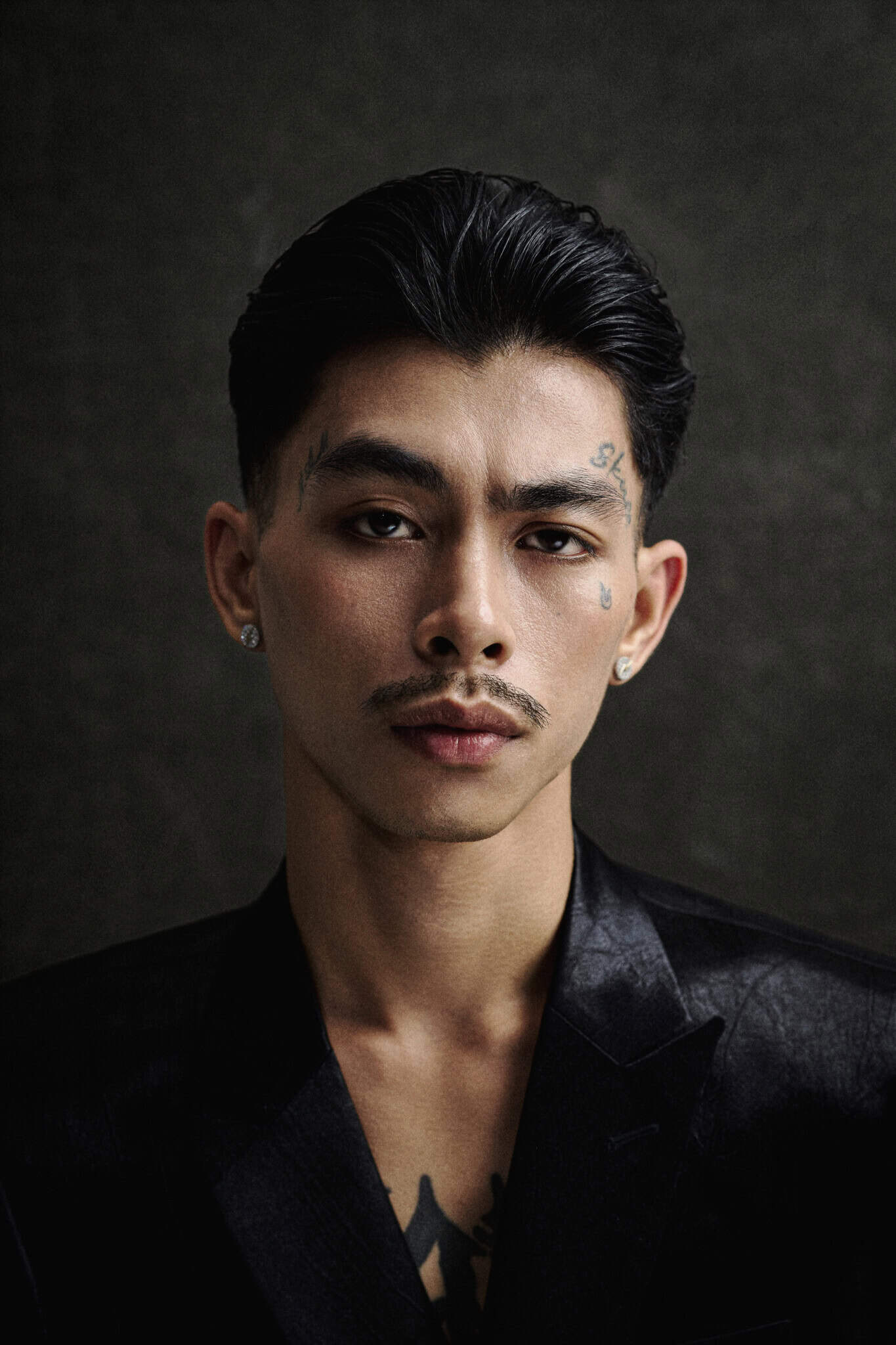 Cambodian rapper VannDa in a black v-neck top, against a dark gray background.