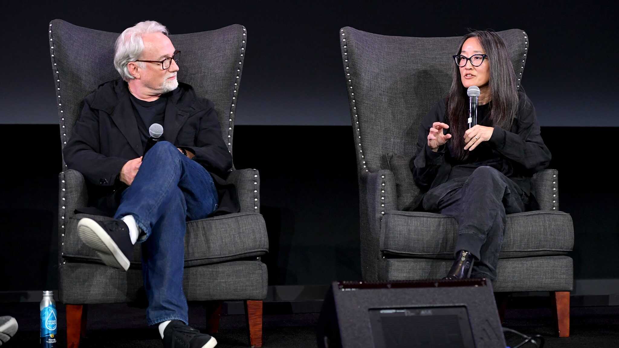 A man and woman sitting in chairs with microphones.