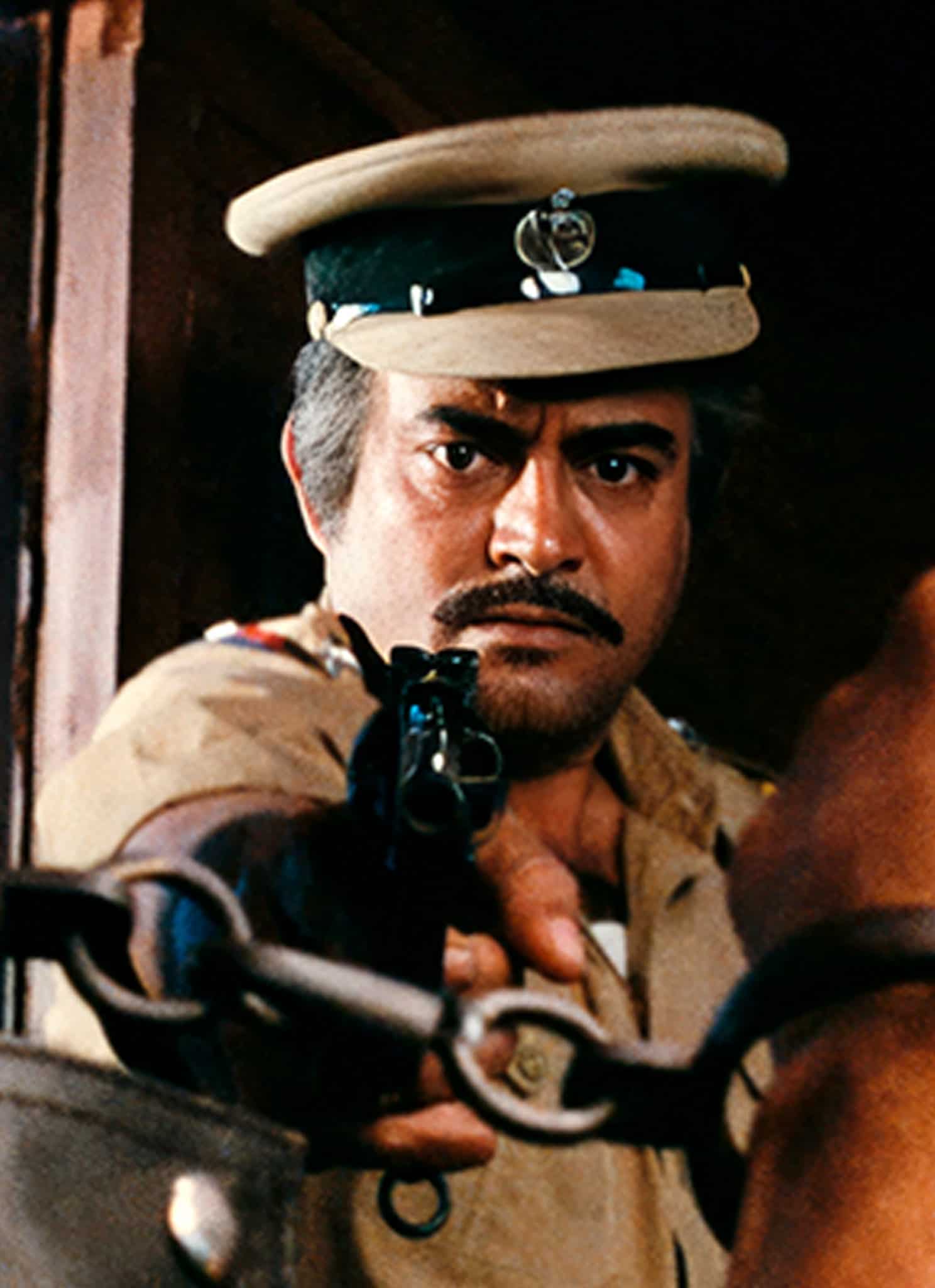 A stern police officer in uniform aims a gun at a person whose hands are held up in steel handcuffs, creating a tense and dramatic scene.