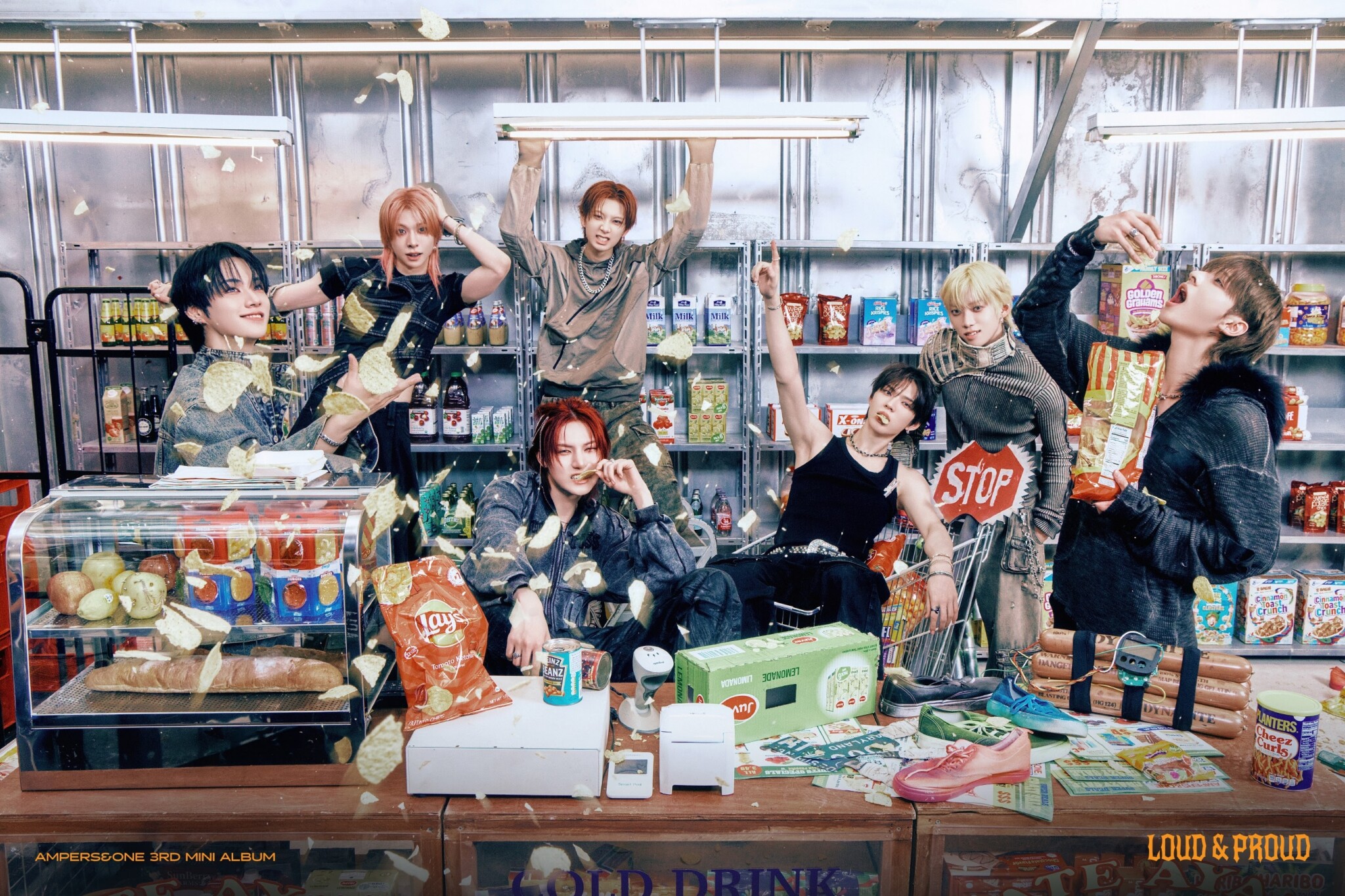 Seven young people pose playfully in a convenience store, tossing chips and snacks in the air, surrounded by shelves of food, drinks, and snacks. The scene is lively and energetic with scattered food.
