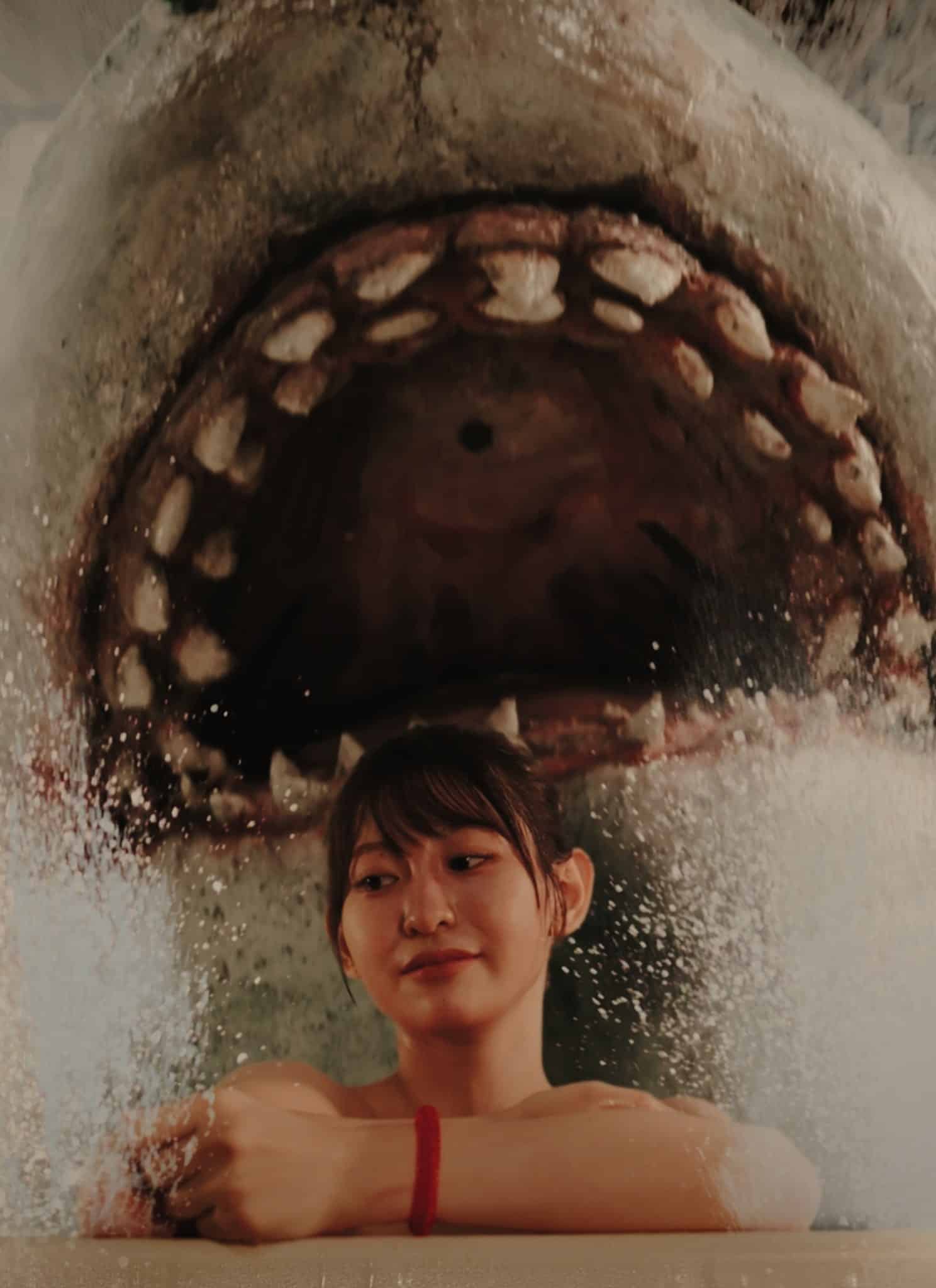 A woman relaxing in a bathtub is unaware of a huge shark with its mouth wide open, emerging from the water behind her. Water splashes dramatically around them.