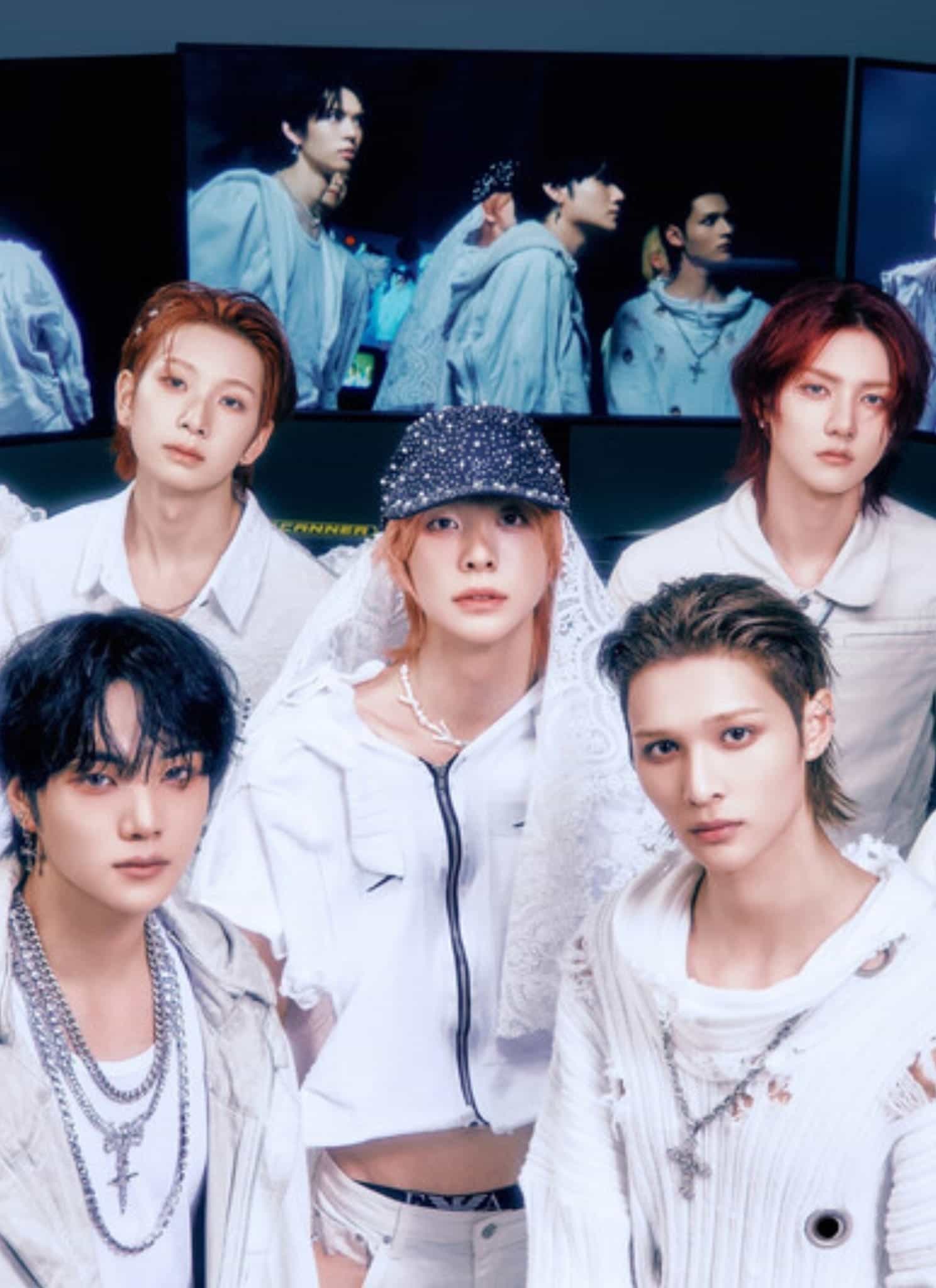 Seven young men wearing stylish white outfits pose together indoors, with several large screens behind them displaying their reflections or similar images. The atmosphere is modern and sleek.