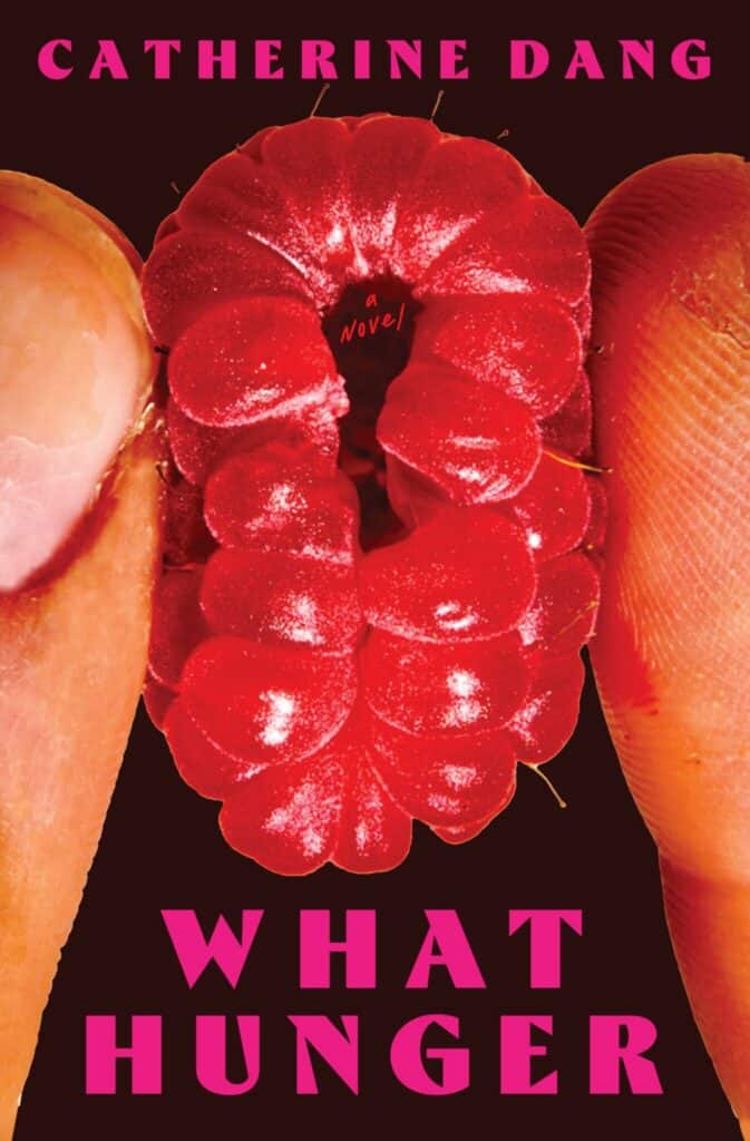 Close-up of two fingers holding a raspberry, with the book title What Hunger and author Catherine Dang in bold pink text. The raspberrys center has the words a novel. The background is black.