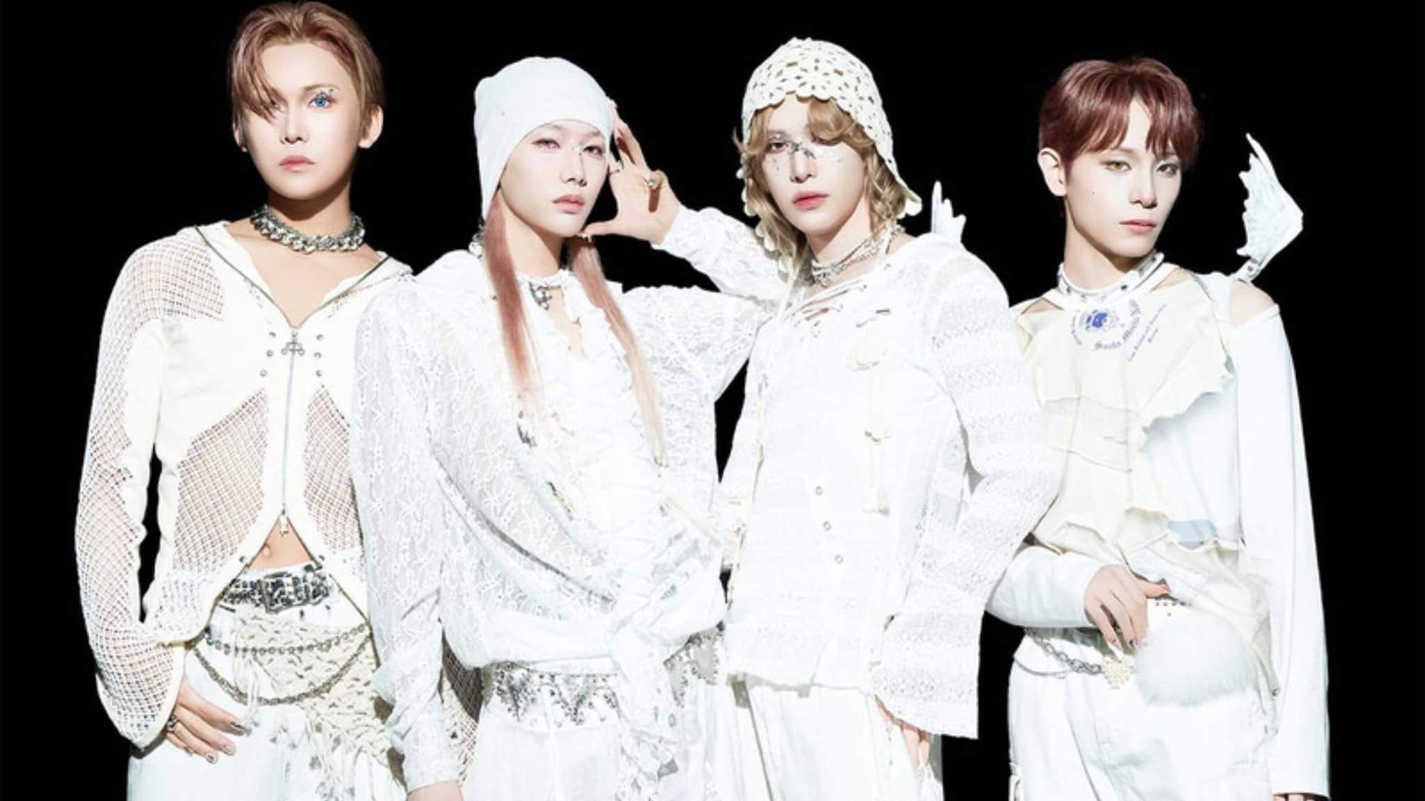 Four people stand against a black background wearing stylish, all-white XLOV outfits with varied textures like mesh and lace, plus layered accessories. Their expressions are serious and their hair is styled fashionably.